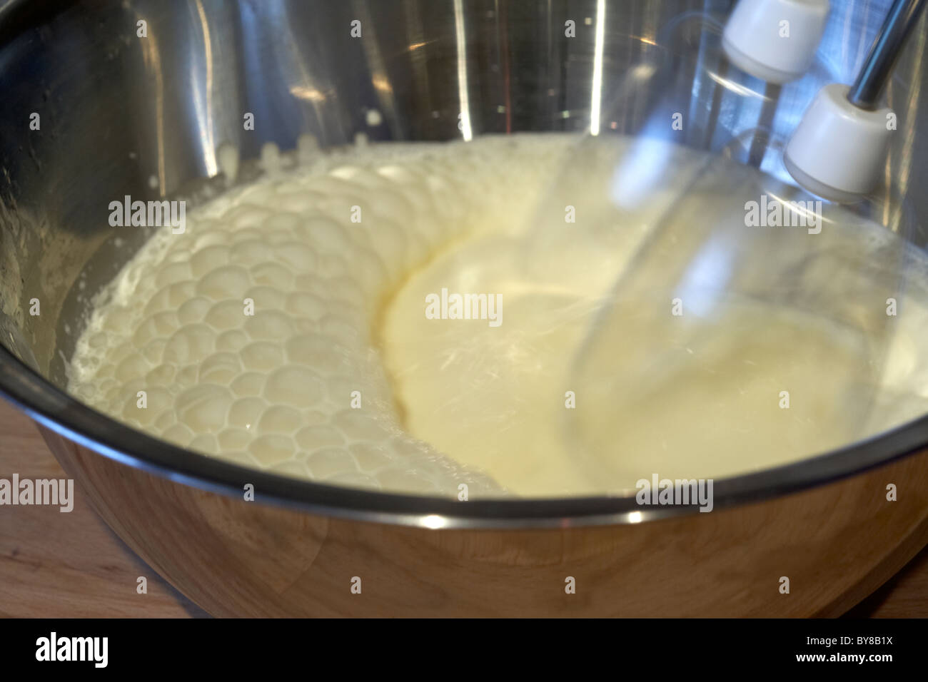 motion blur photo of electric whisk whisking fresh whipping cream in a