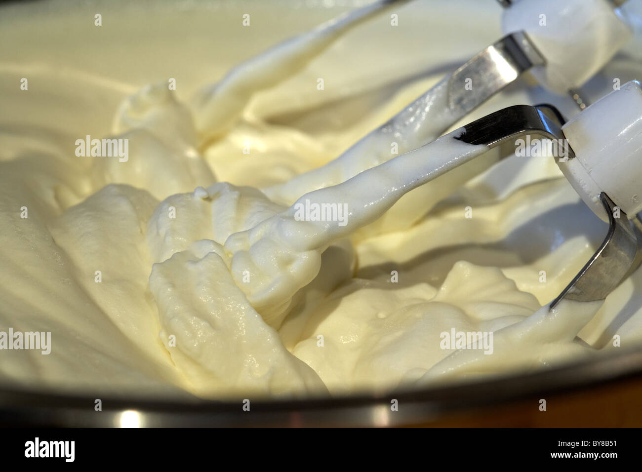 fresh whipping cream whipped up in a metal mixing bowl by an electric