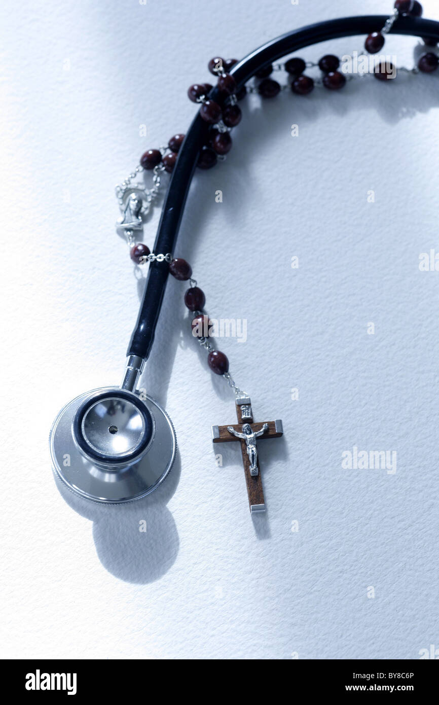 a stethoscope and a rosary entwined,  medical science versus the church or religion Stock Photo