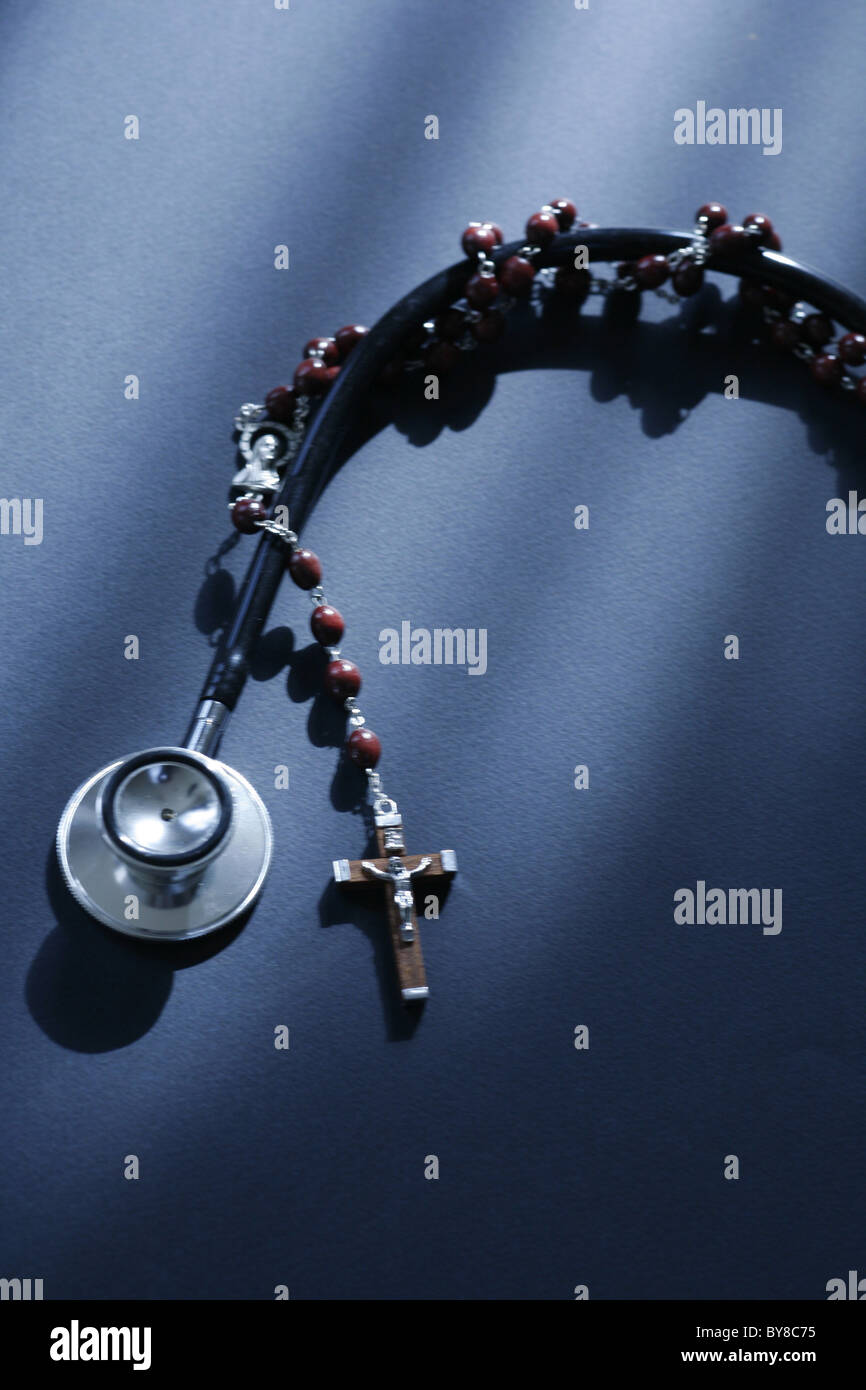 a stethoscope and a rosary entwined modern medical science versus religion Stock Photo
