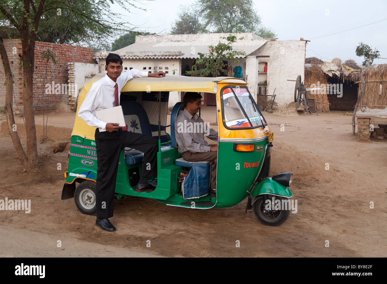 India, Uttar Pradesh, Agra, young businessman with laptop posing next to auto rickshaw on journey from home to work Stock Photo