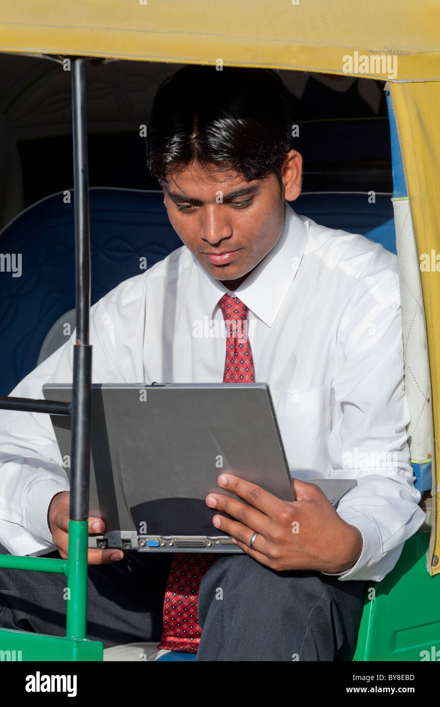 India, Uttar Pradesh, Agra, Indian businessman sitting in auto-rickshaw using laptop Stock Photo