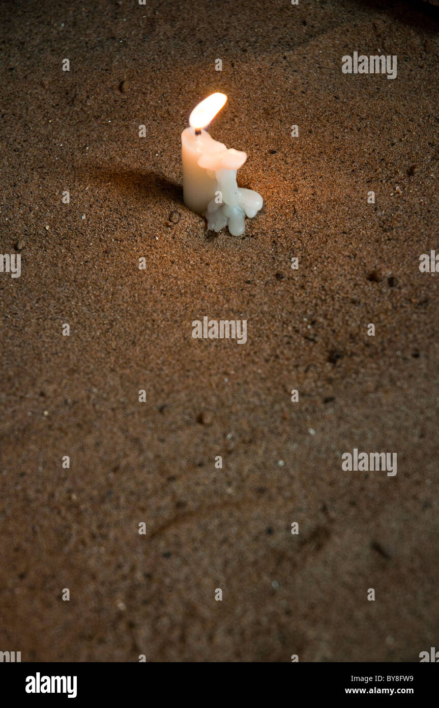 Lit candle in sand Stock Photo Alamy