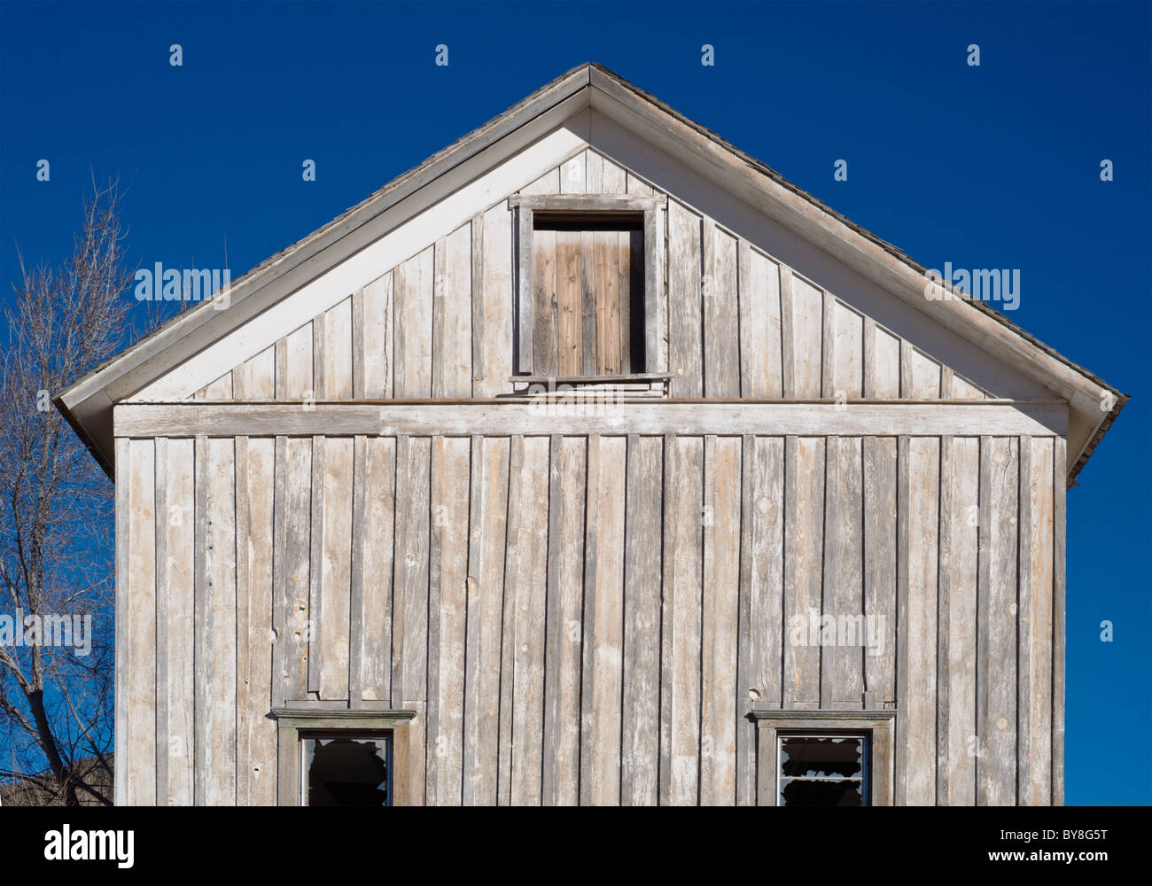 An old wooden building stands under a blue sky, on the Mescalero