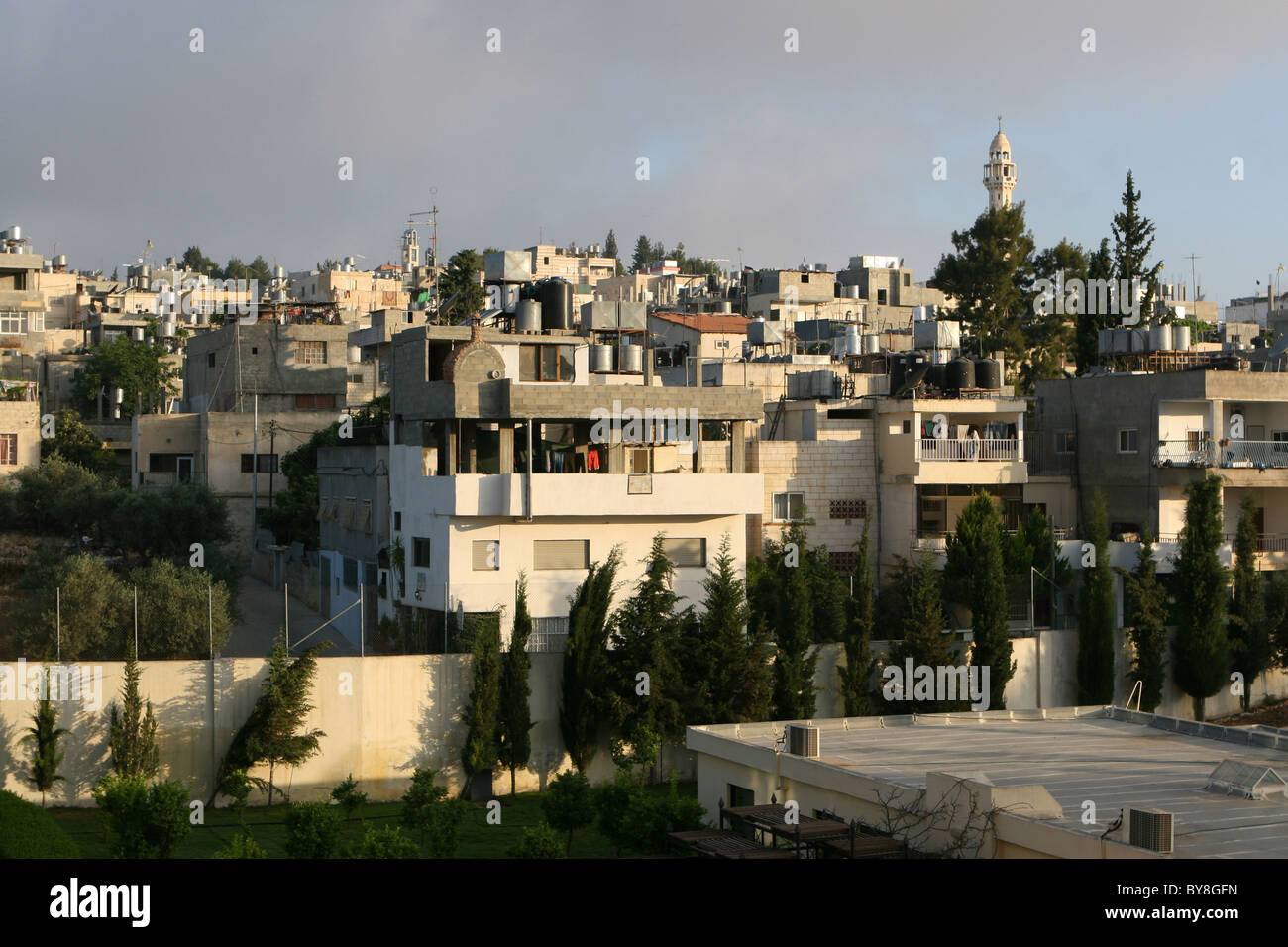 Multistory homes of Palestinians rise compactly across this hilltop in Bethlehem, Israel. A multitude of solar water heaters sit Stock Photo