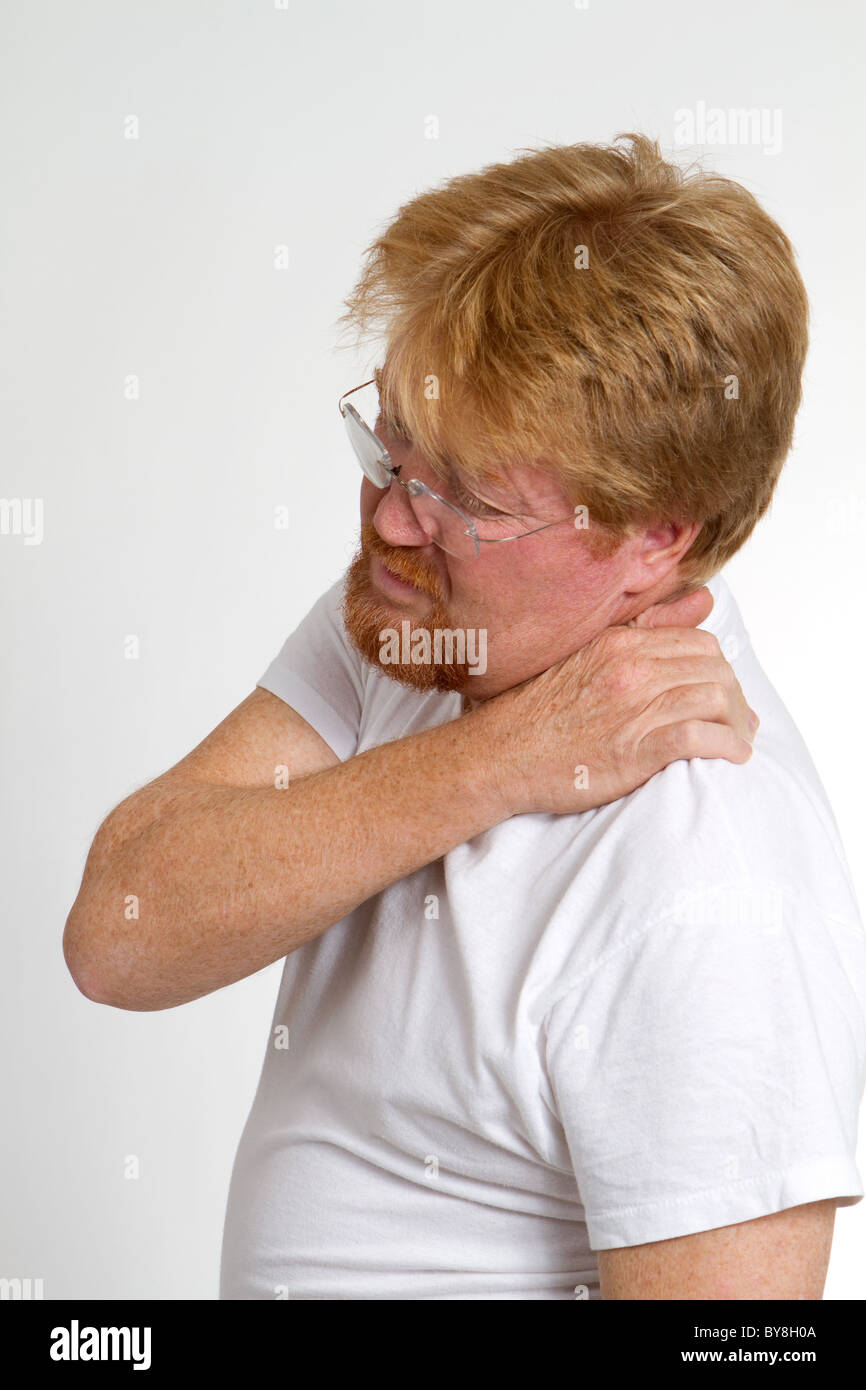 Mature man massages and squeezes his shoulder in pain. Stock Photo