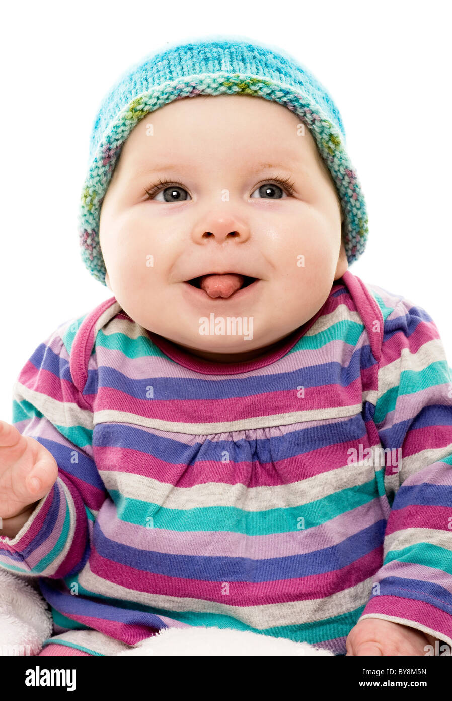 Head and shoulders shot of caucasian baby, dressed in bright stripy clothes, sticking it's tongue out. Stock Photo