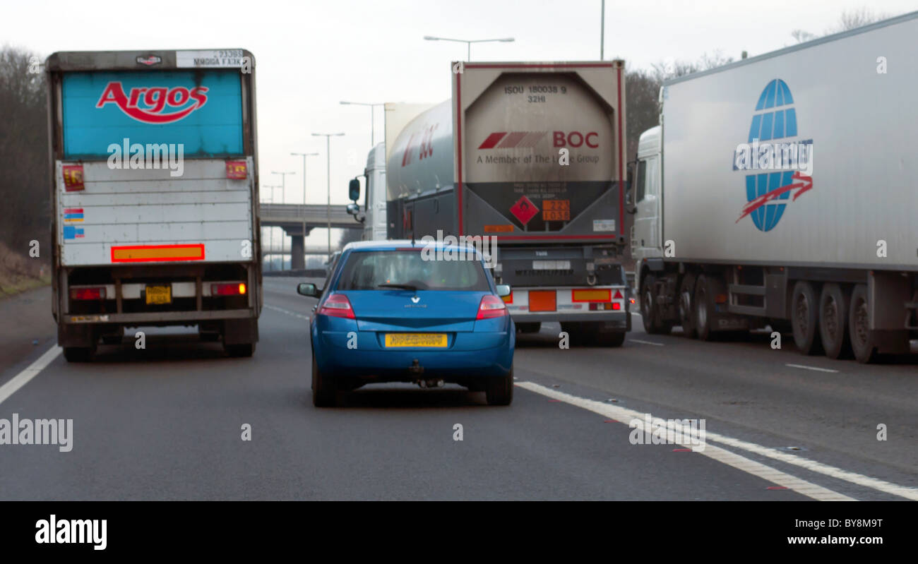 Aggressive  and Dangerous Car Driver Driving into Merging Motorway Lane behind Lorries Stock Photo