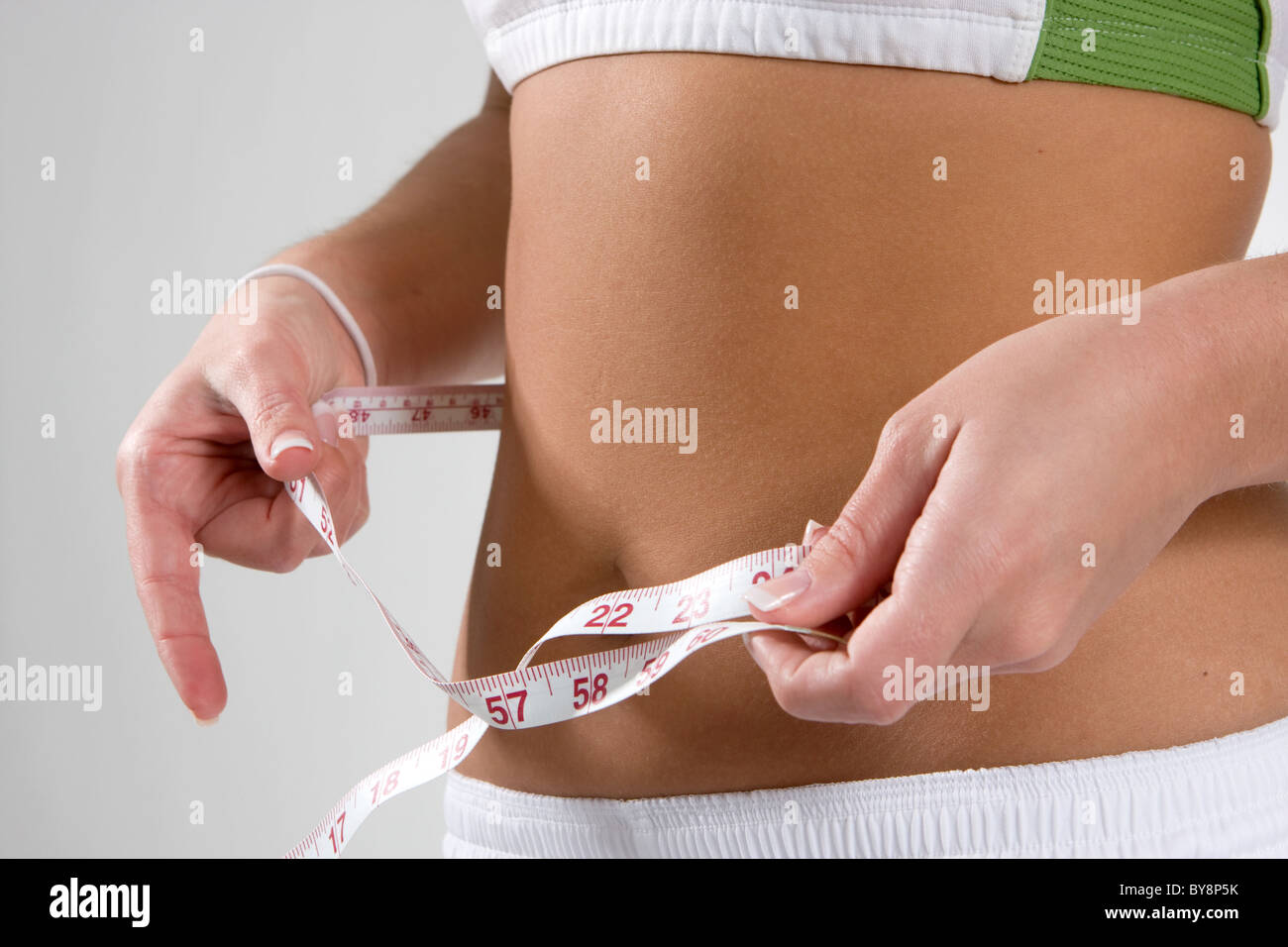 Fit young woman checks her waist size with a cloth tape measure. Stock Photo