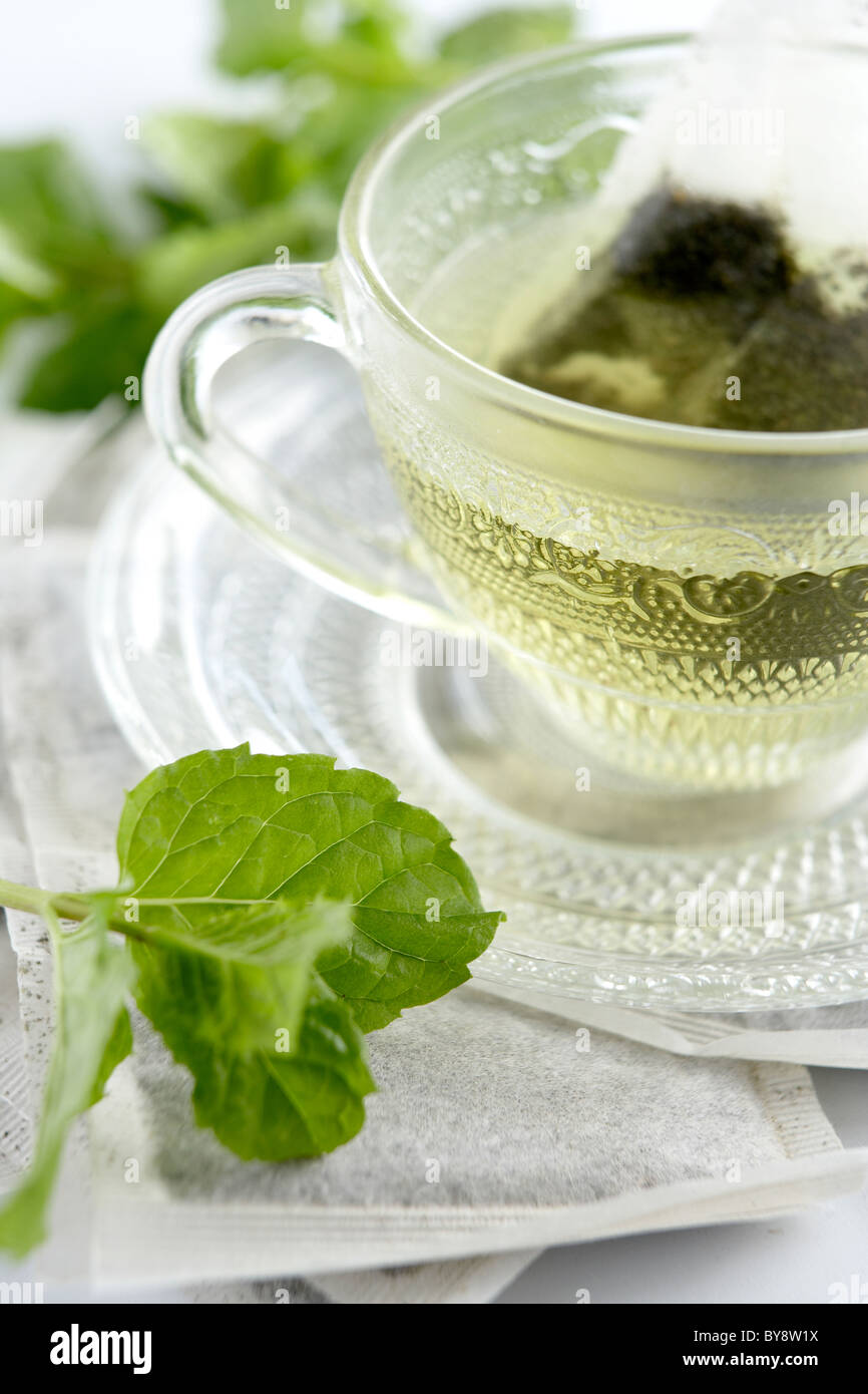 Mint tea in glass tea cup on mint tea bags surrounded with mint leaves Stock Photo