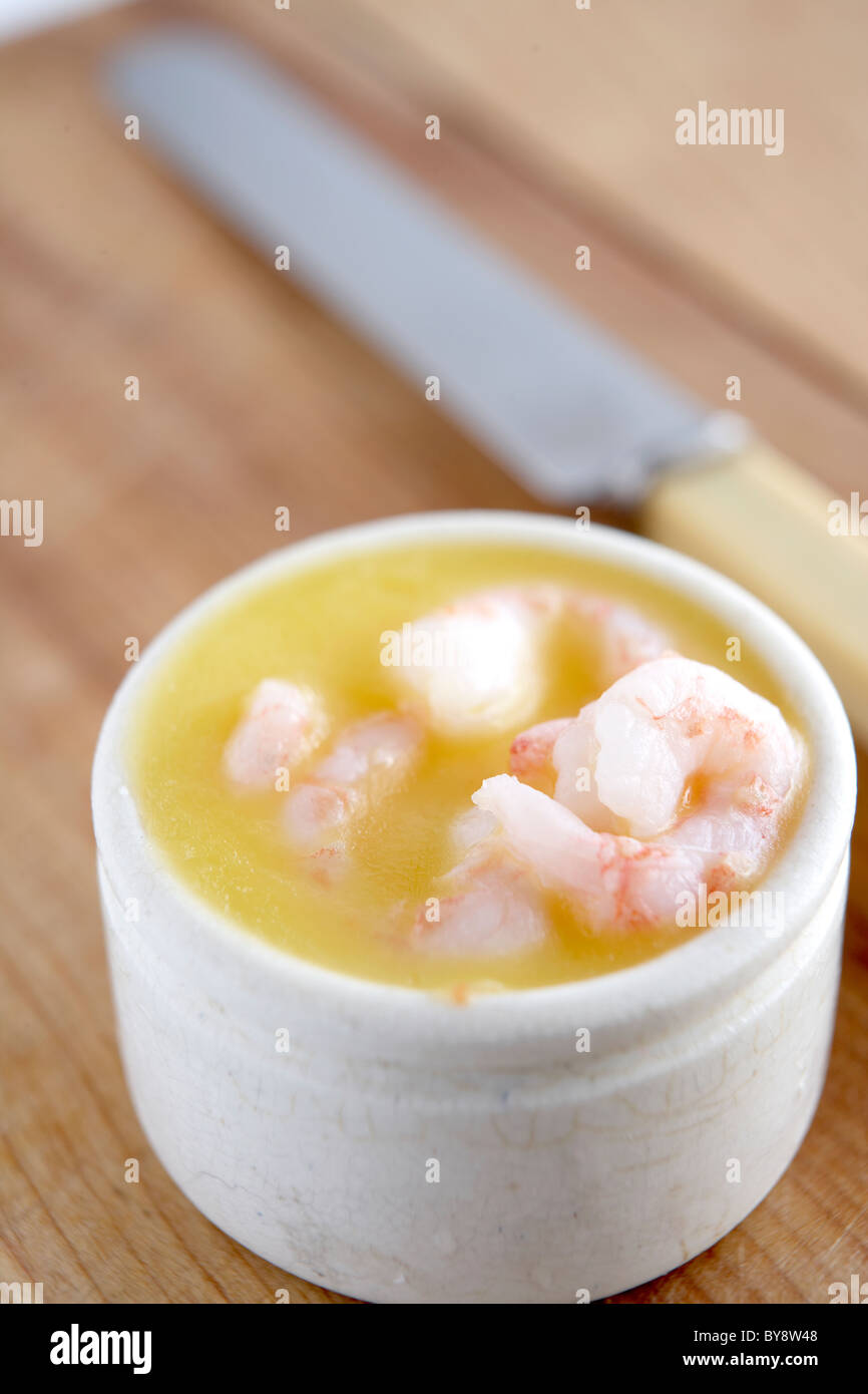 Potted prawns in white container on wooden background with knife Stock Photo