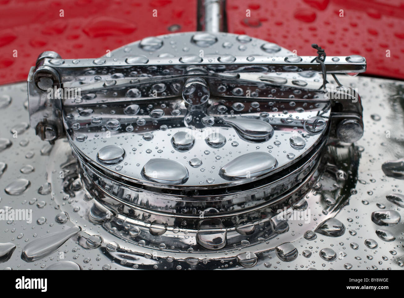 Droplet Radiator The chrome radiator cap of a classic car after a rain shower. There are ...