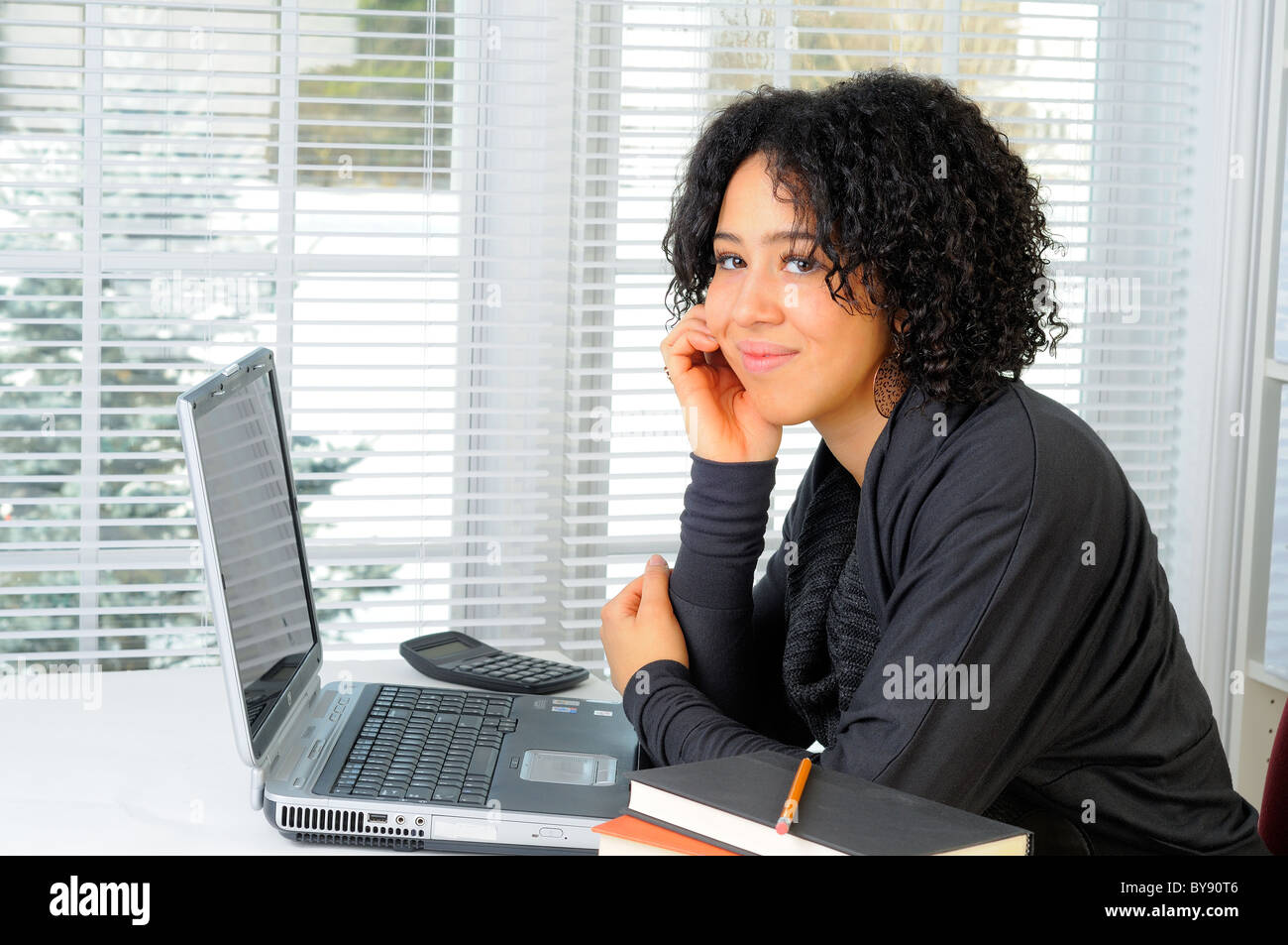 Young Woman Sat At Her Desk Using A Laptop Computer Stock Photo