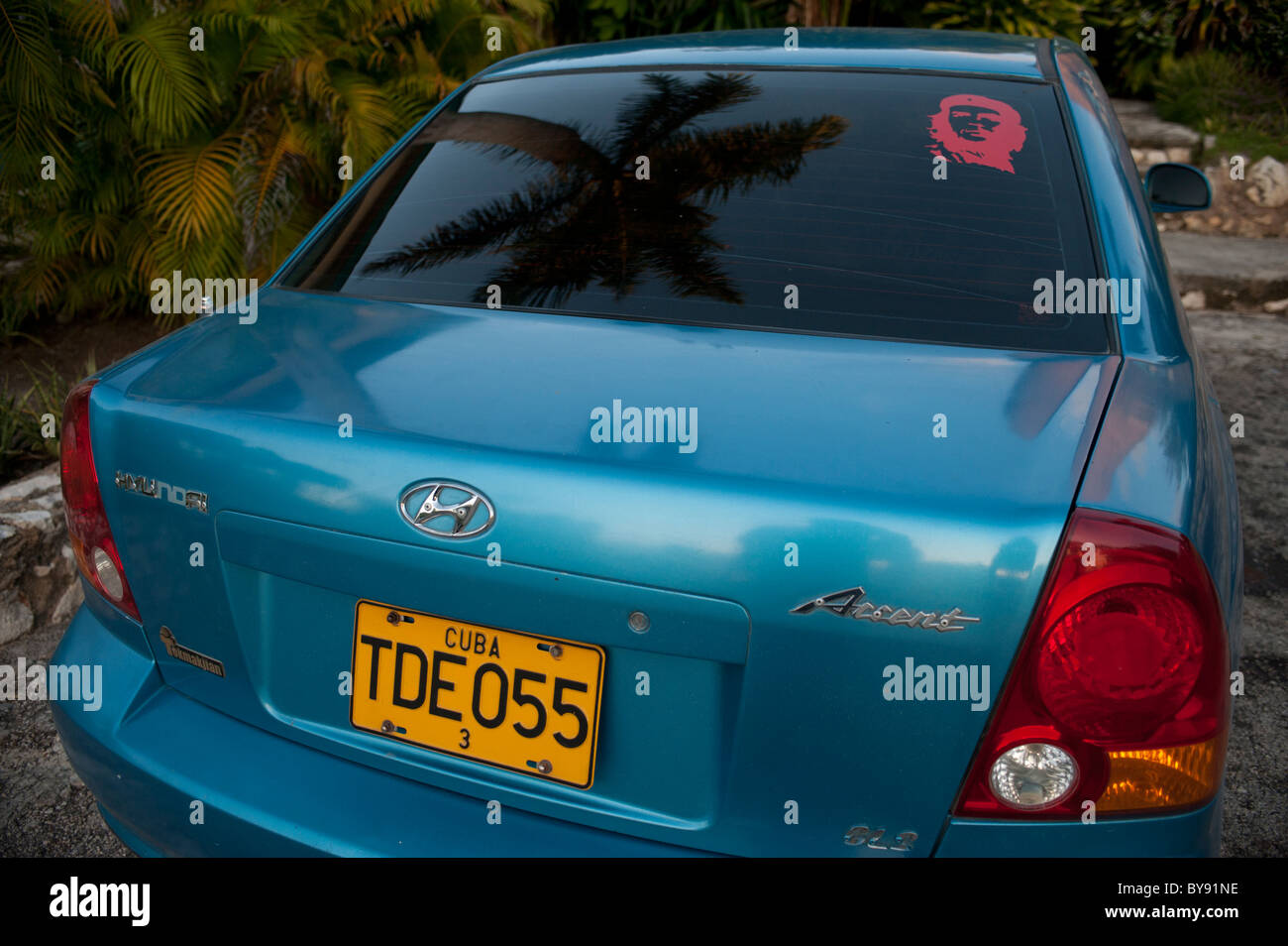 Blue Honda accent in Cuba with che Guevarra sticker and palmtree reflection Stock Photo