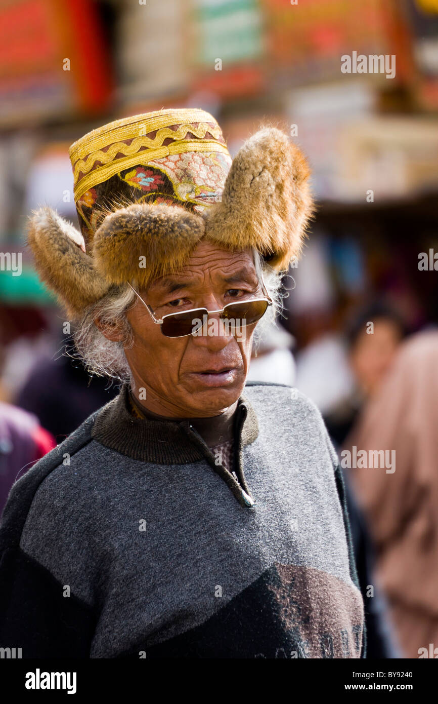 Old Tibetan man pilgrim wearing fur trimmed yellow hat in the Barkhor Lhasa Tibet. JMH4478 Stock Photo