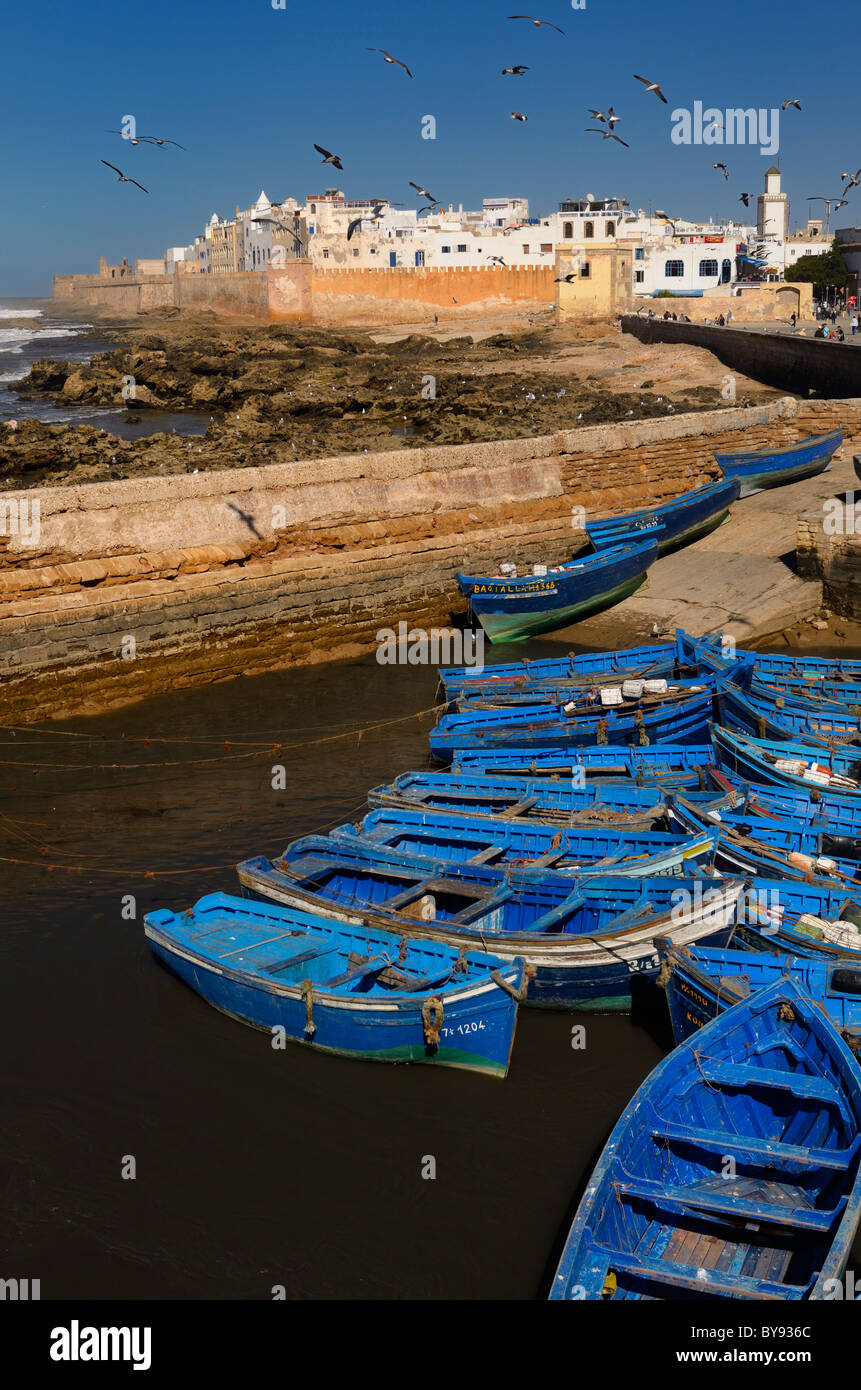Blue fishing boats and the Atlantic sea bastion ramparts of Essaouira Morocco Stock Photo
