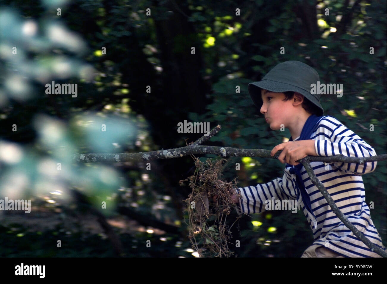 Boy running in the forest holding a tree branch, Provence, France. Stock Photo