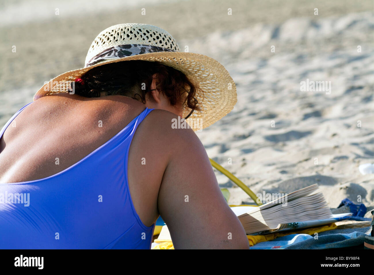 Woman lying on the beach reading a novel, Camargue, France. Stock Photo