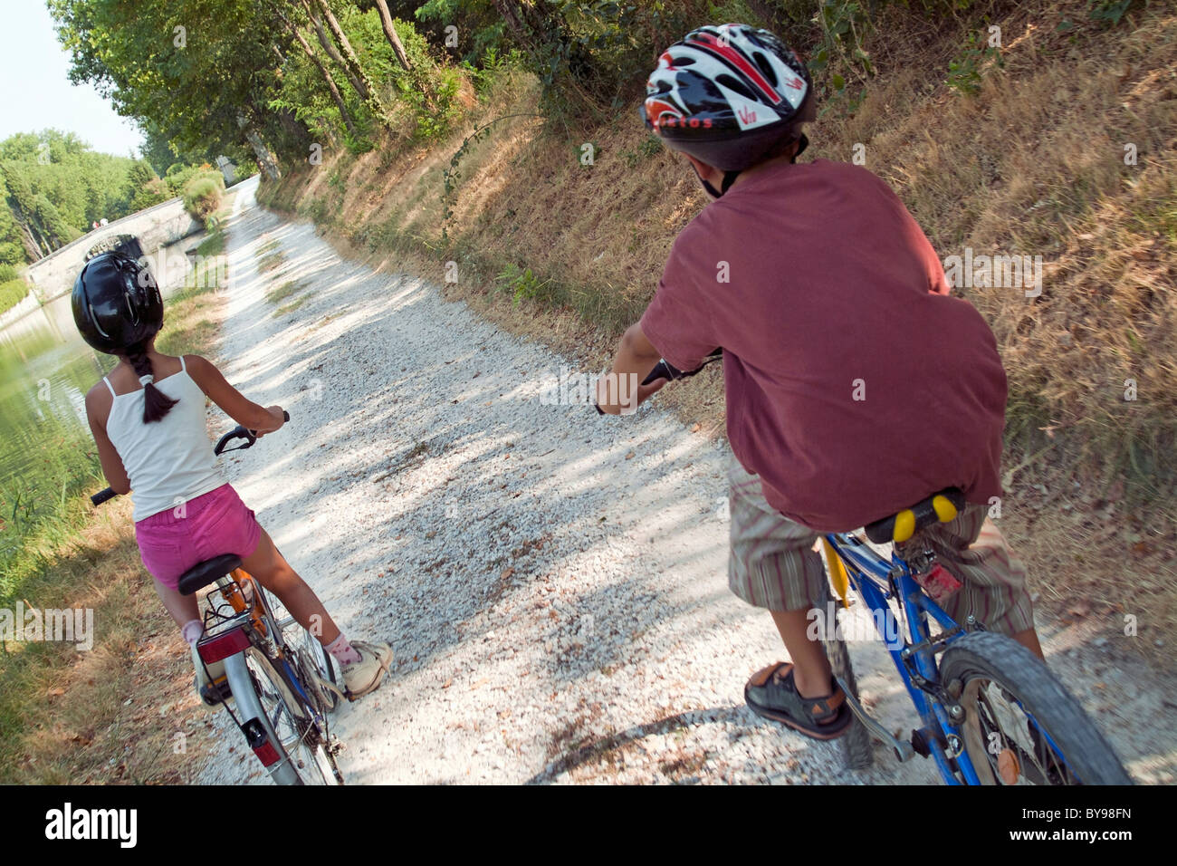 Young boy and girl biking side by side, Carcassonne, Canal du Midi, France. Stock Photo