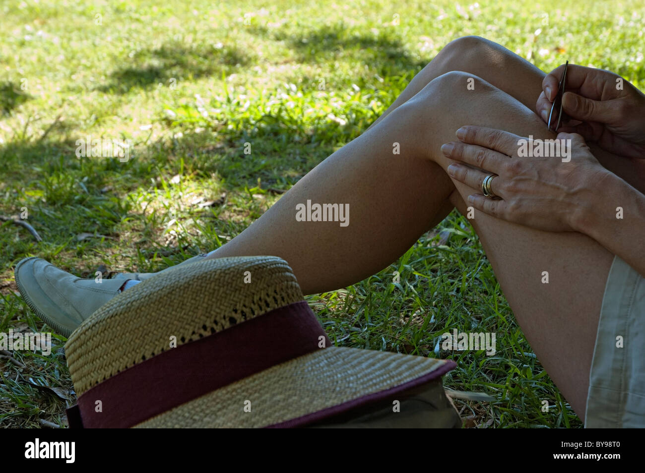Woman removing hair from her legs with tweezers, France. Stock Photo
