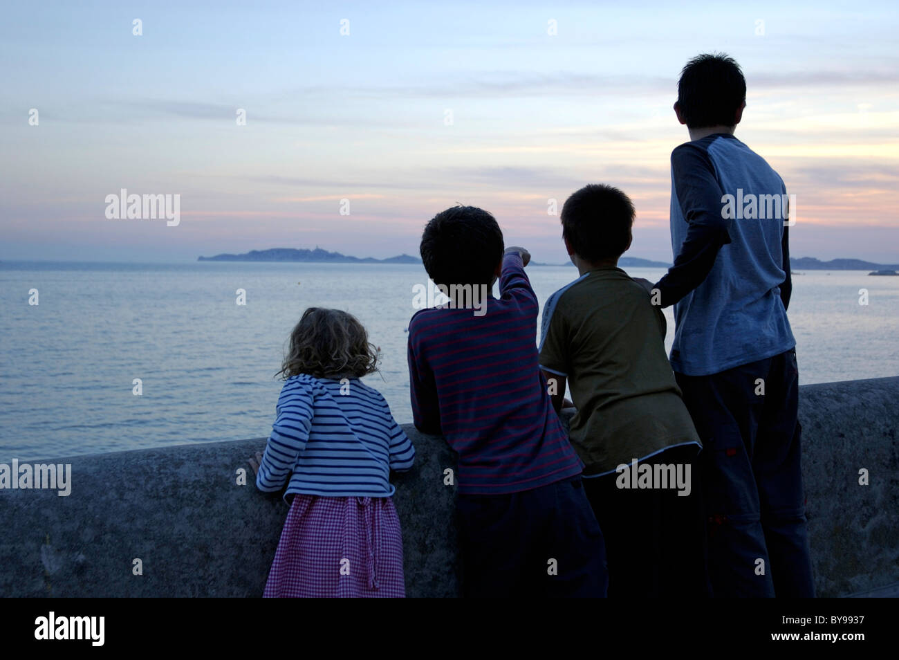 Four children watching the sunset over the Frioul archipelago, Marseille, France. Stock Photo