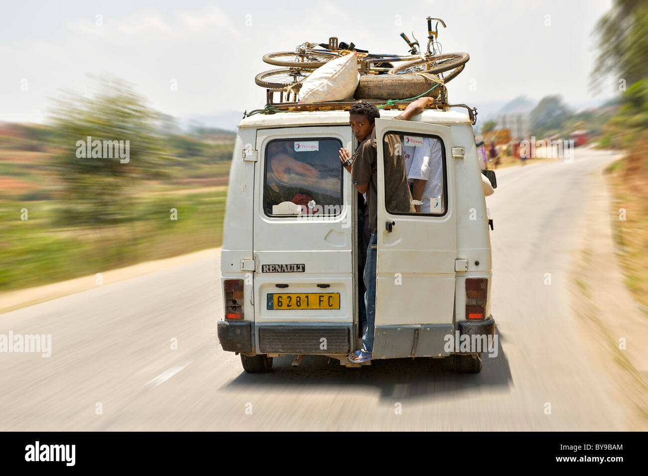 A Man Hanging Out The Open Rear Door Of A Taxi Brousse Bush