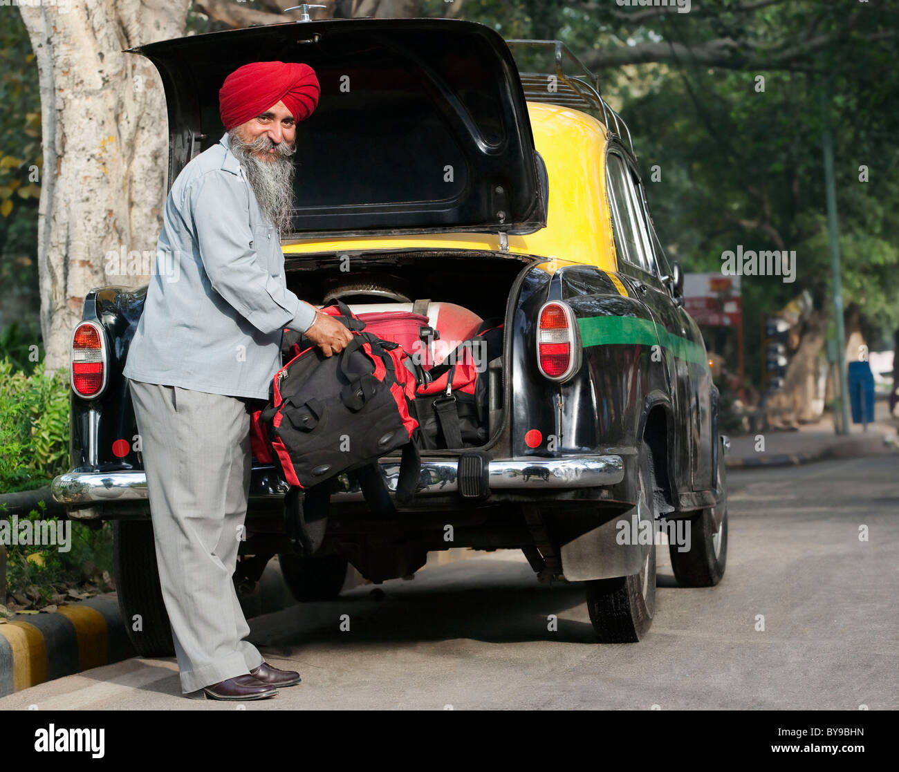 Sikh taxi driver loading luggage into the dickie Stock Photo
