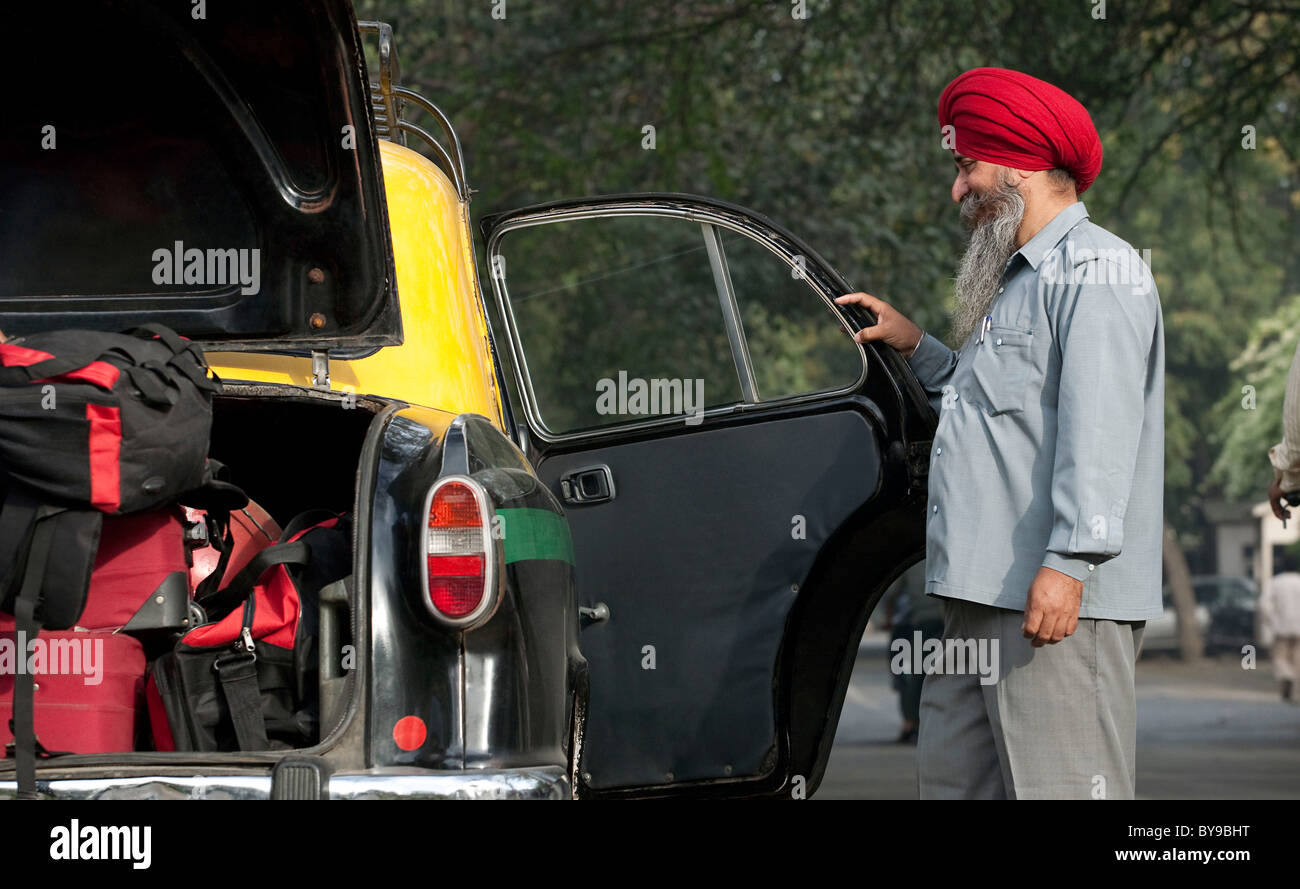 Sikh taxi driver holding the door of the vehicle open Stock Photo