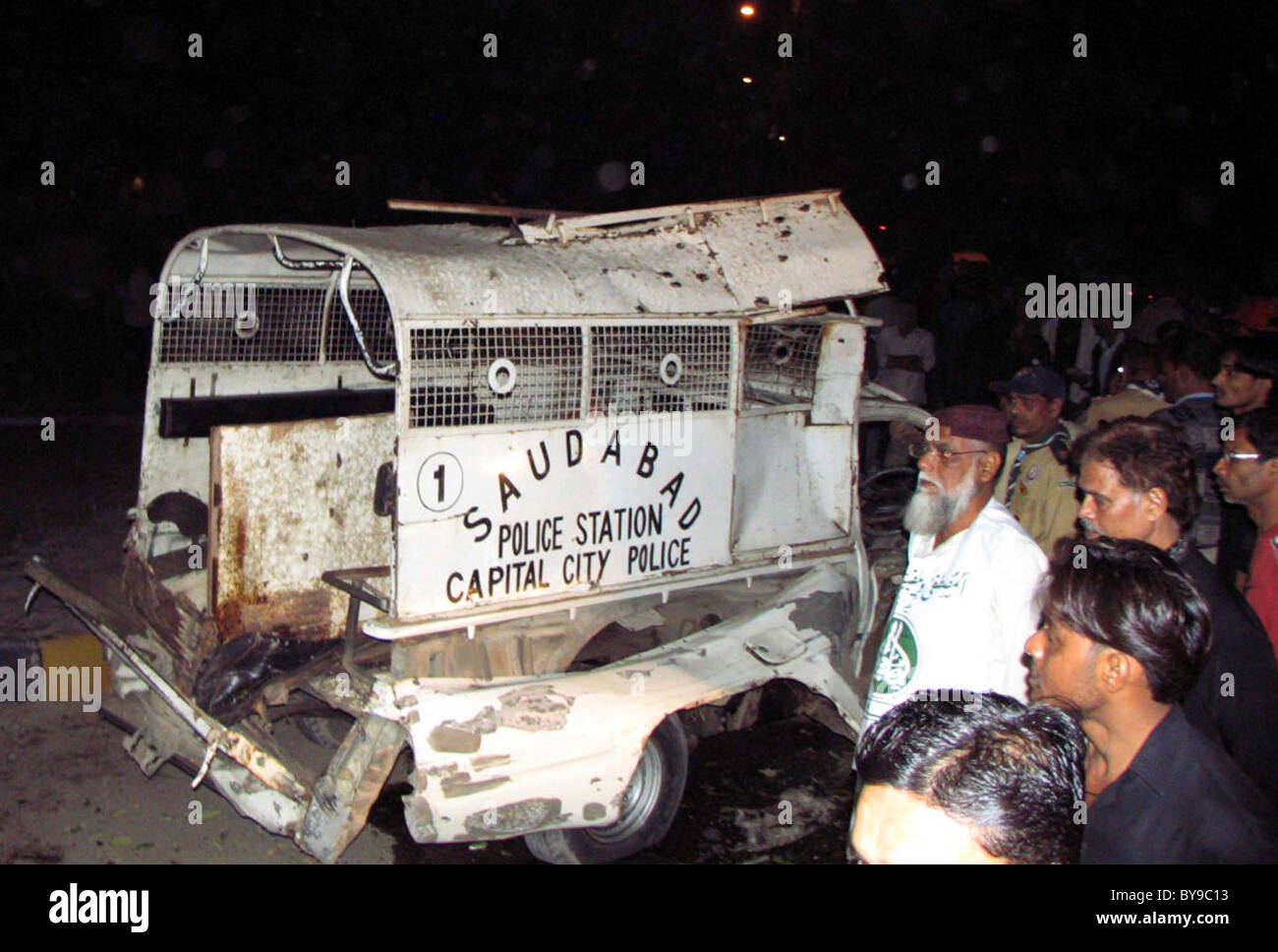 People look damaged police vehicle which was destroyed in explosion after explosion at the site in Karachi Stock Photo