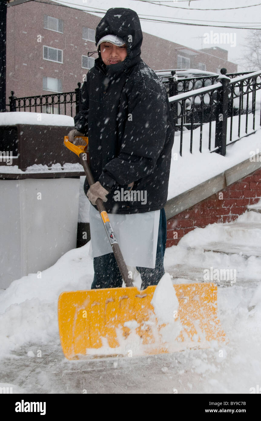 Robin Caron of Wakefield, MA, shovels the walkway in front of the grocery store where he works