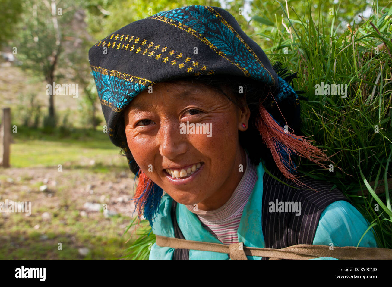 Young peasant woman carrying the harvest on her back, portrait, Tibet, Central Asia Stock Photo