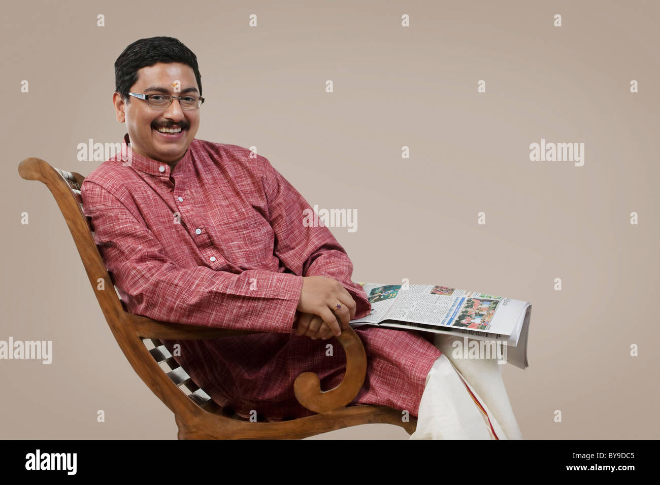 South Indian man sitting on a chair with a newspaper Stock Photo - Alamy