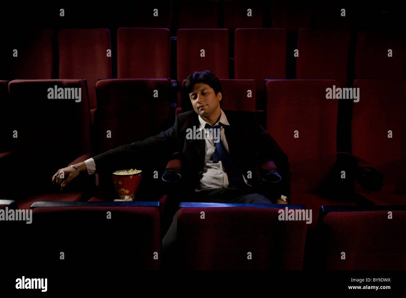 Businessman sleeping inside a cinema hall Stock Photo