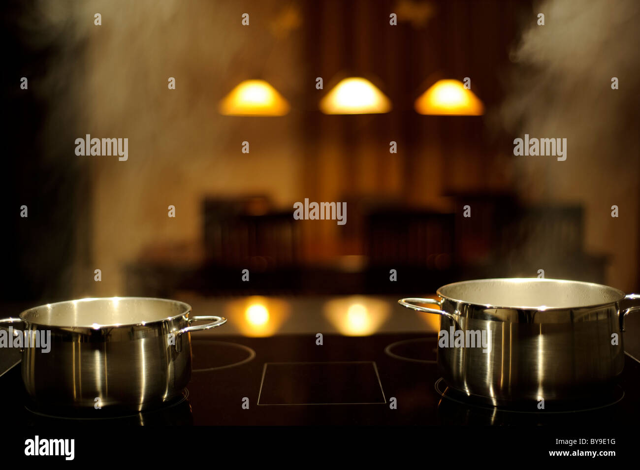 Two stainless steel pots on a induction stove with steam, table on