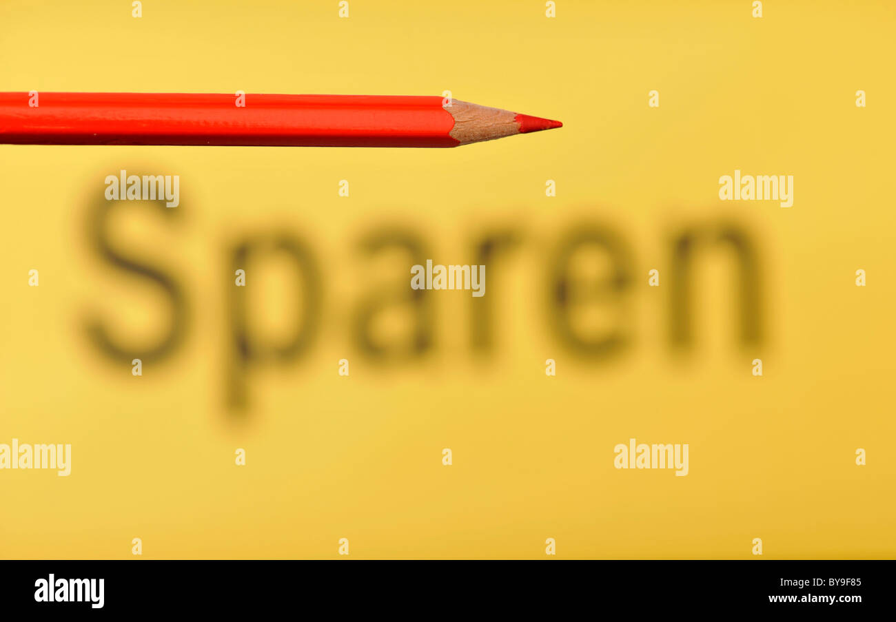 Red pencil in front of the out of focus word Sparen, German for Saving Stock Photo