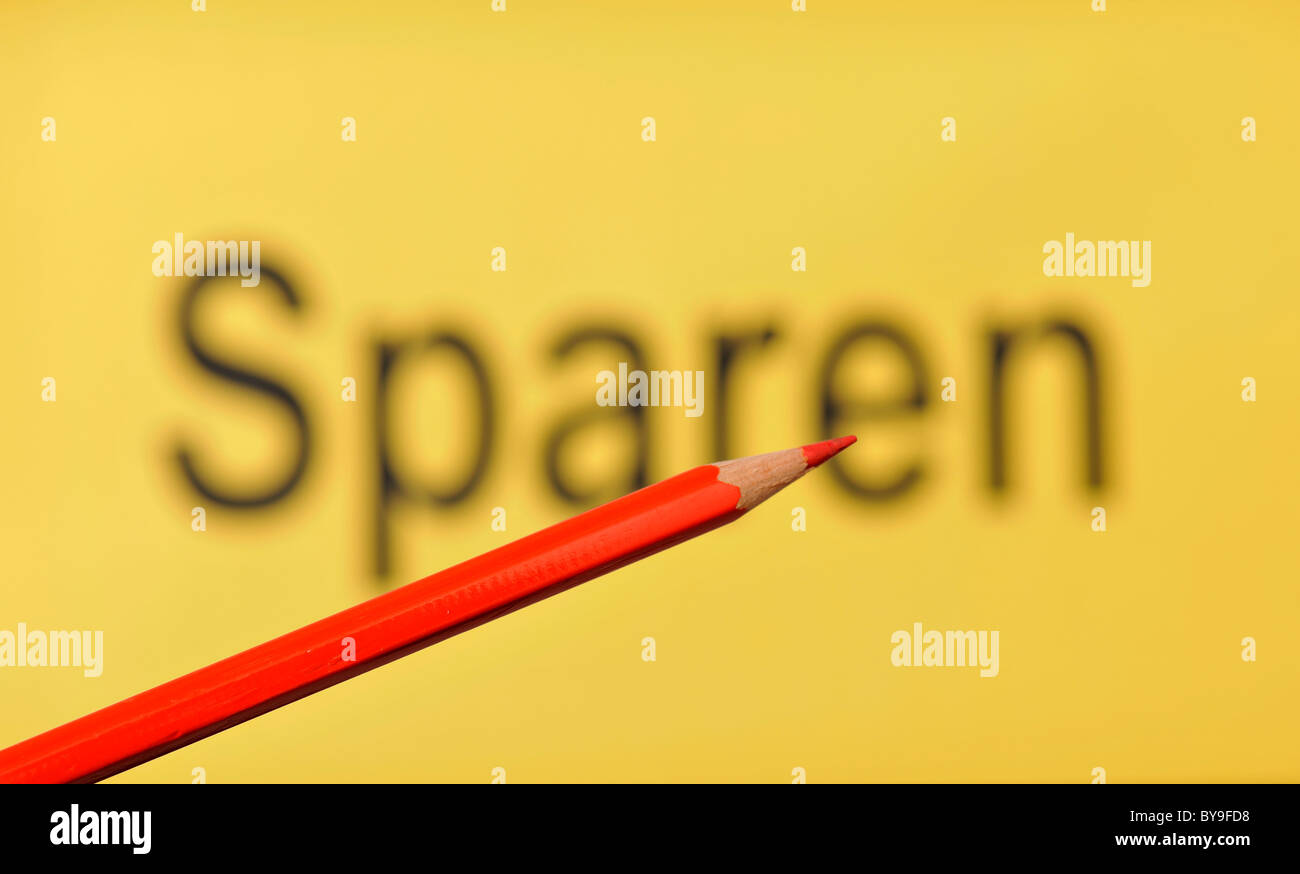 Red pencil in front of the out of focus word Sparen, German for Saving Stock Photo