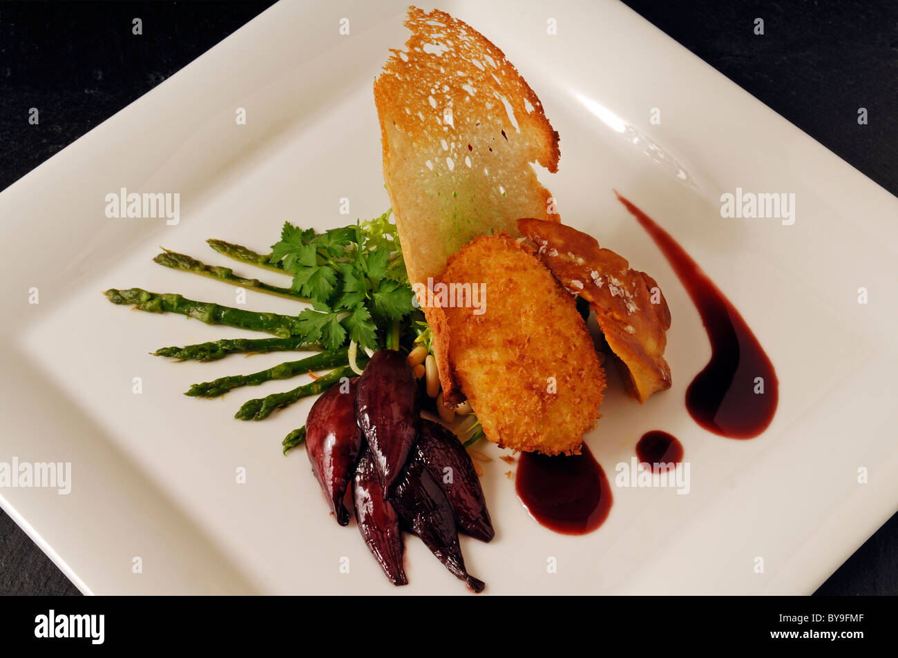 Roasted duck liver with poached baked egg, wild asparagus and red onion confit served on a white