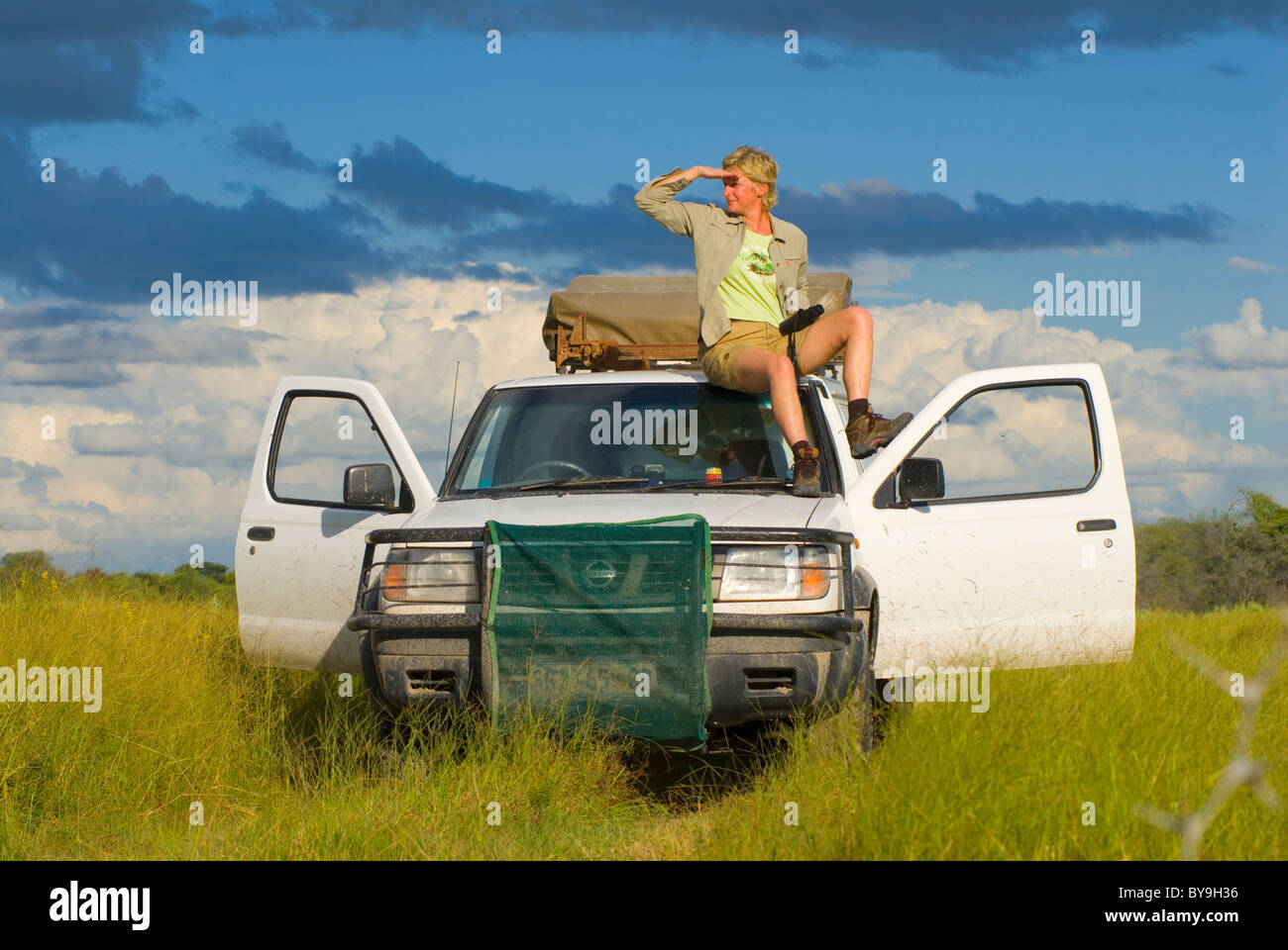 tourist sitting on four wheel drive vehicle whatching the area on a safari, Makgadikgadi National Park, Botswana, Africa Stock Photo