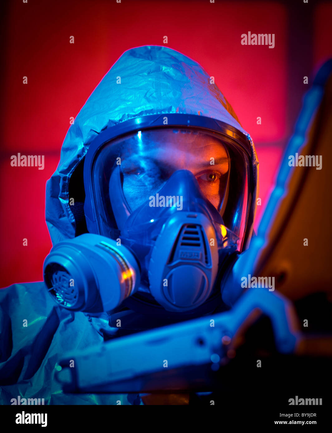 Man wearing a face gas mask dressed in a chemical warfare suit using a