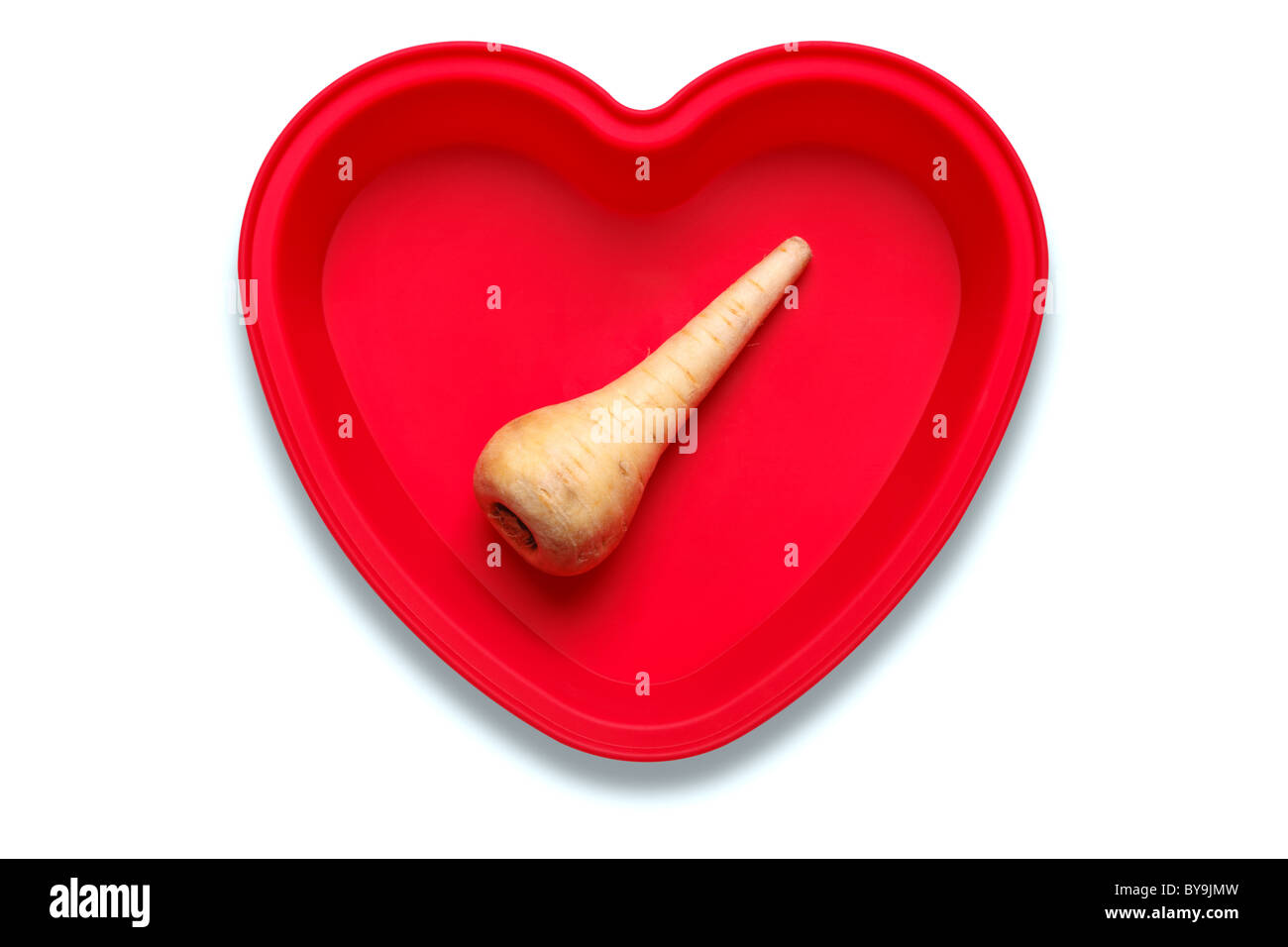 Conceptual photo of a parsnip in a heart shaped dish to represent a love of the vegetable, isolated on a white background Stock Photo