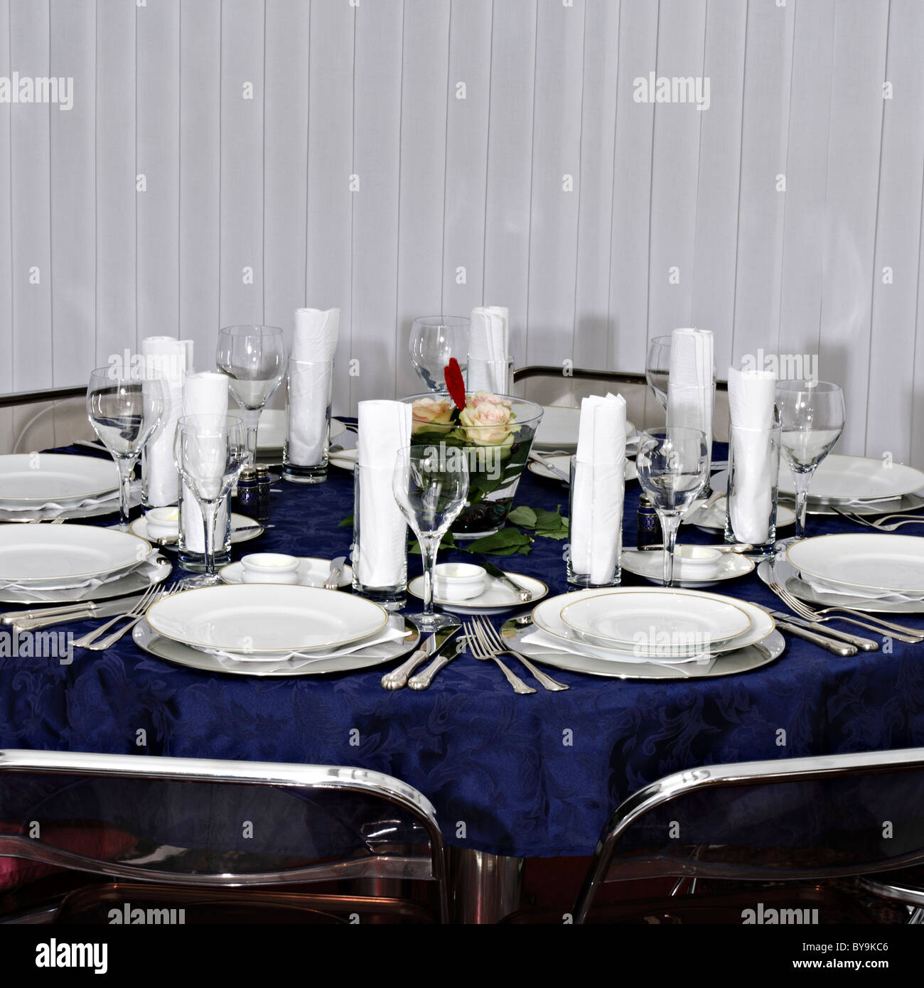 Table setting vase with flower floating in water, silverware and blue