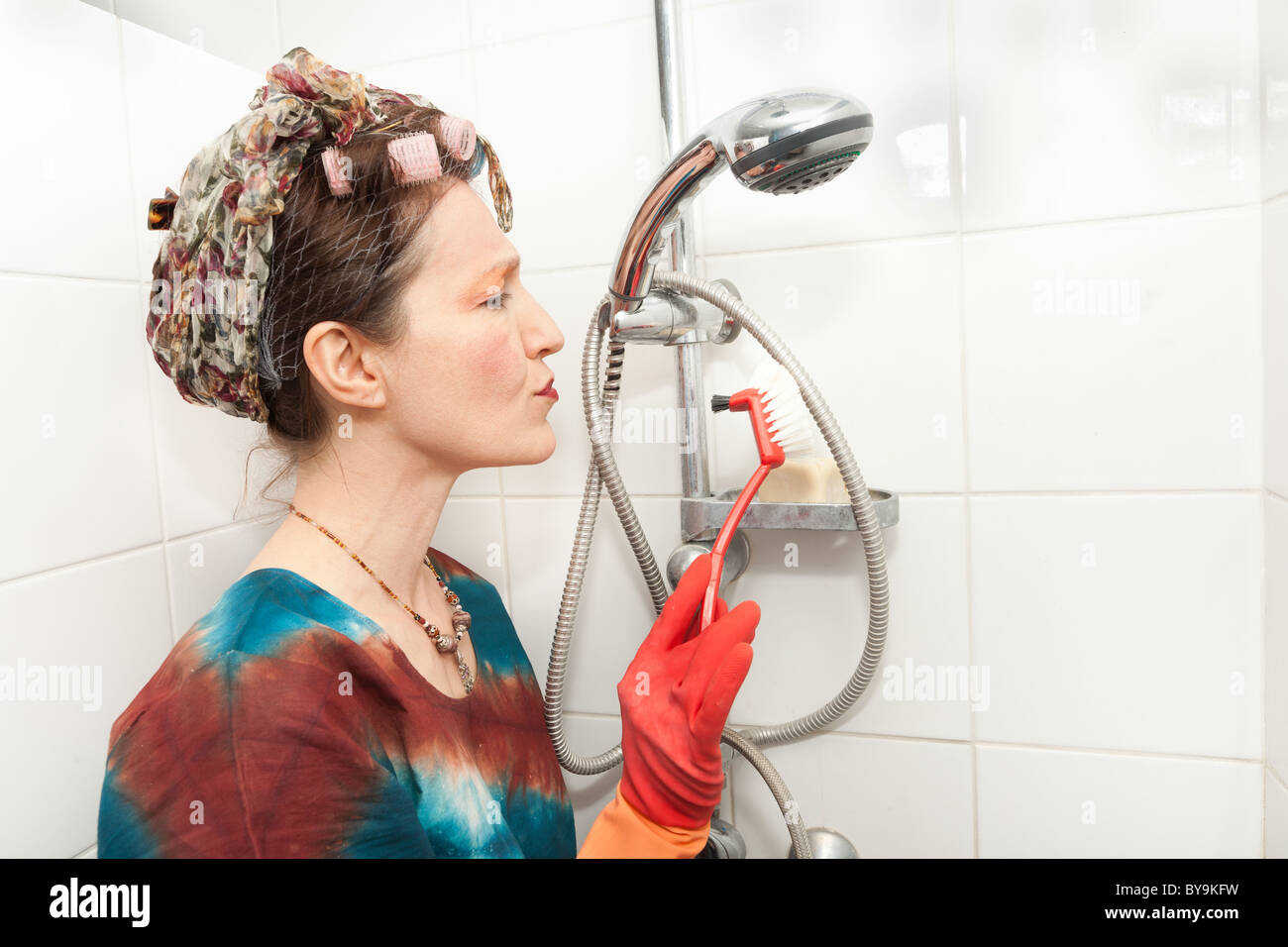 funny woman cleaning bathroom shower with brush Stock Photo