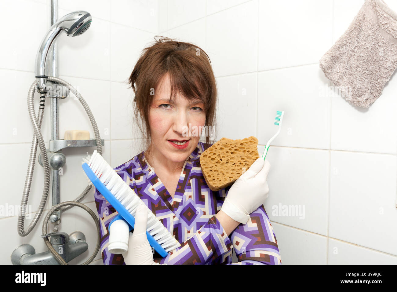 funny woman holding brushes ready to wash bathroom shower Stock Photo