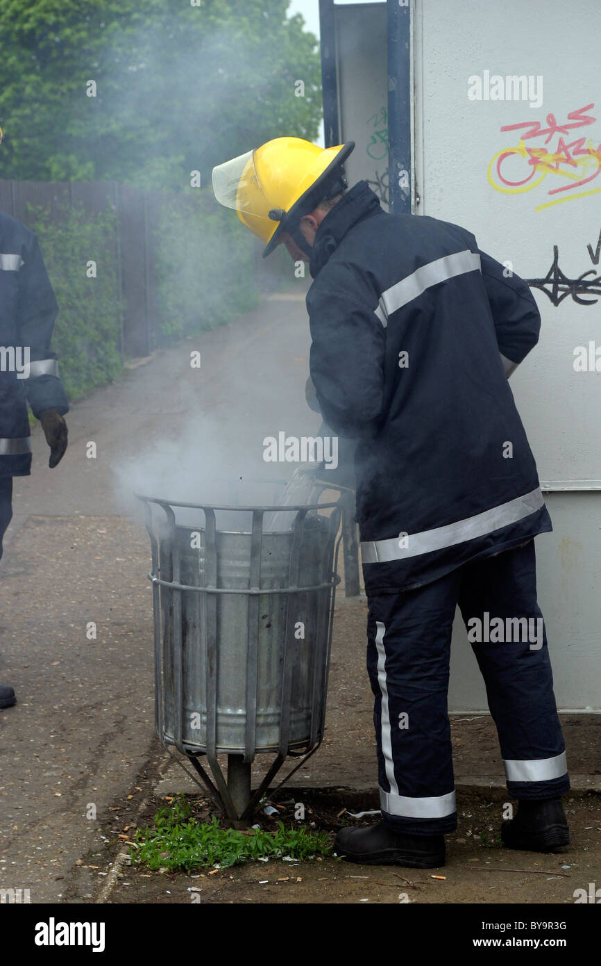 Fireman putting out a bin fire Stock Photo Alamy