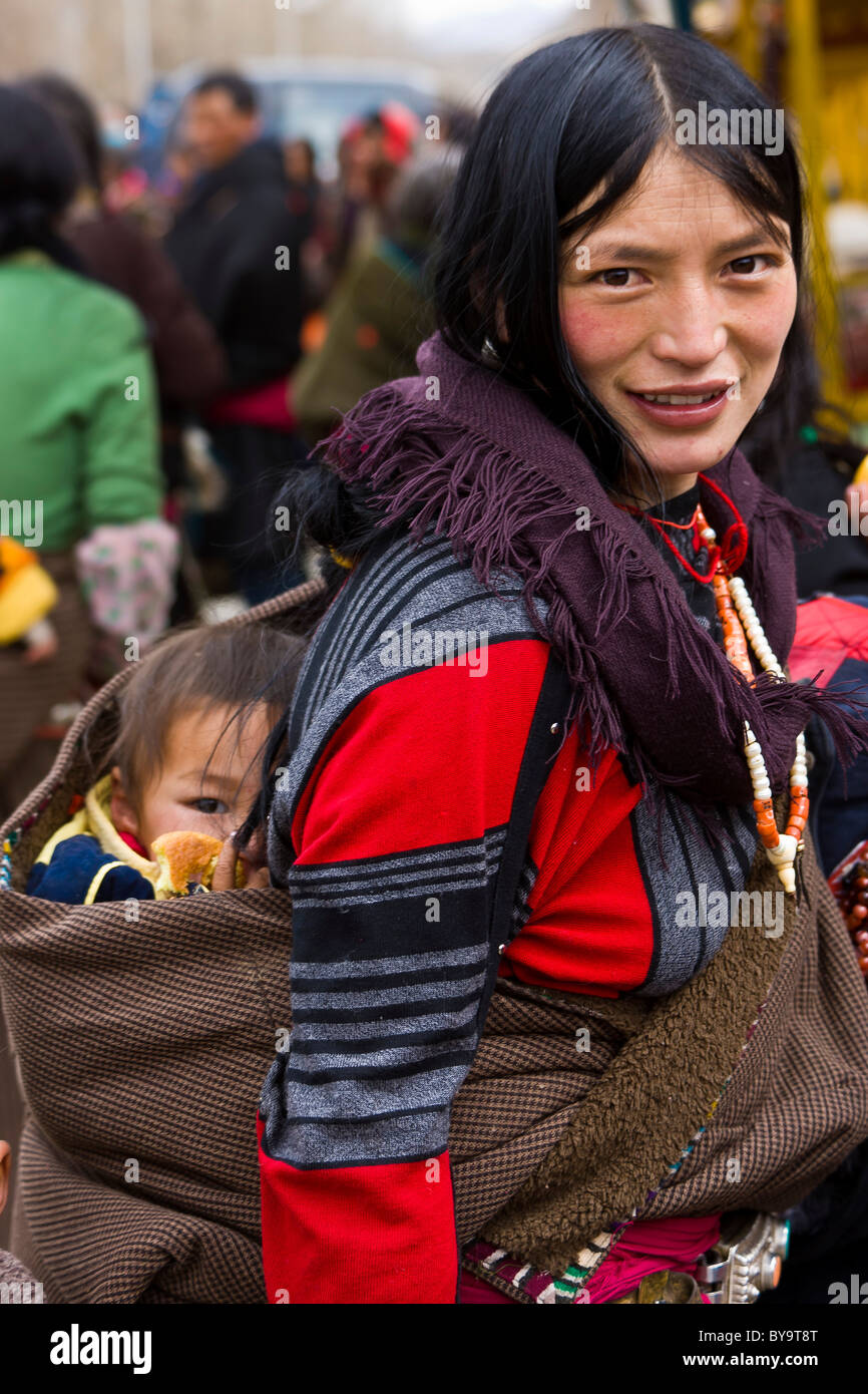 Tibetan woman with child in papoose on her back Norbulingka or Jewel Park, Tagten Migyur Podrang, Lhasa, Tibet, China. JMH4722 Stock Photo