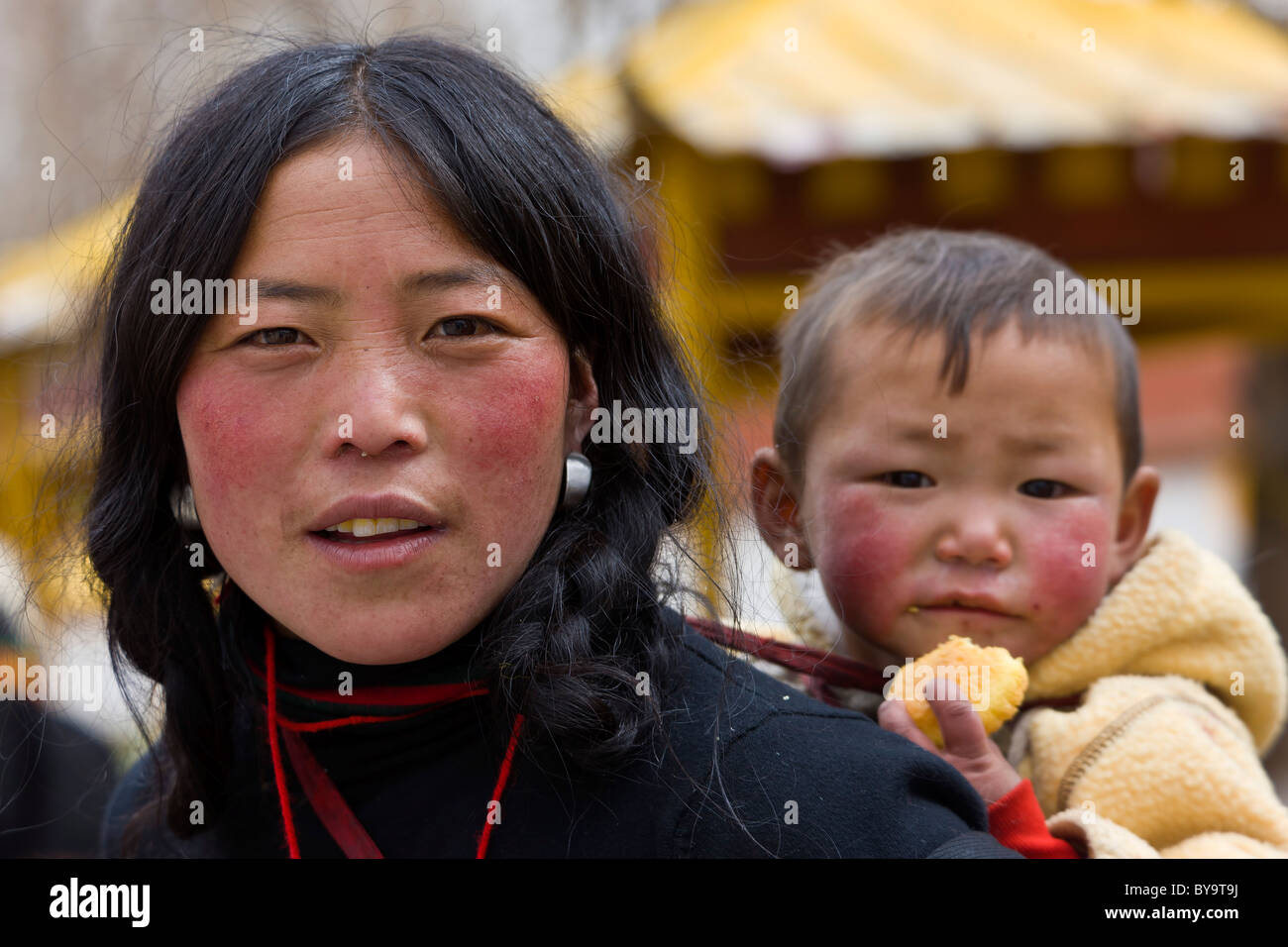 Tibetan woman with child in papoose on her back Norbulingka or Jewel Park, Tagten Migyur Podrang, Lhasa, Tibet, China. JMH4724 Stock Photo
