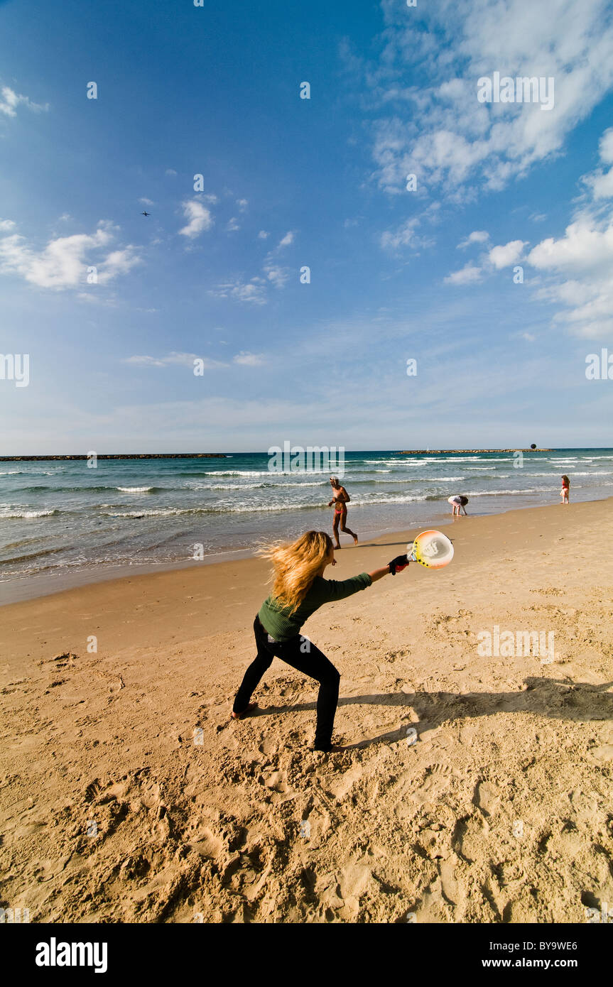 An Israeli woman playing ' Matkot ' - beach Tennis on a sunny winter day in tel Aviv. Stock Photo
