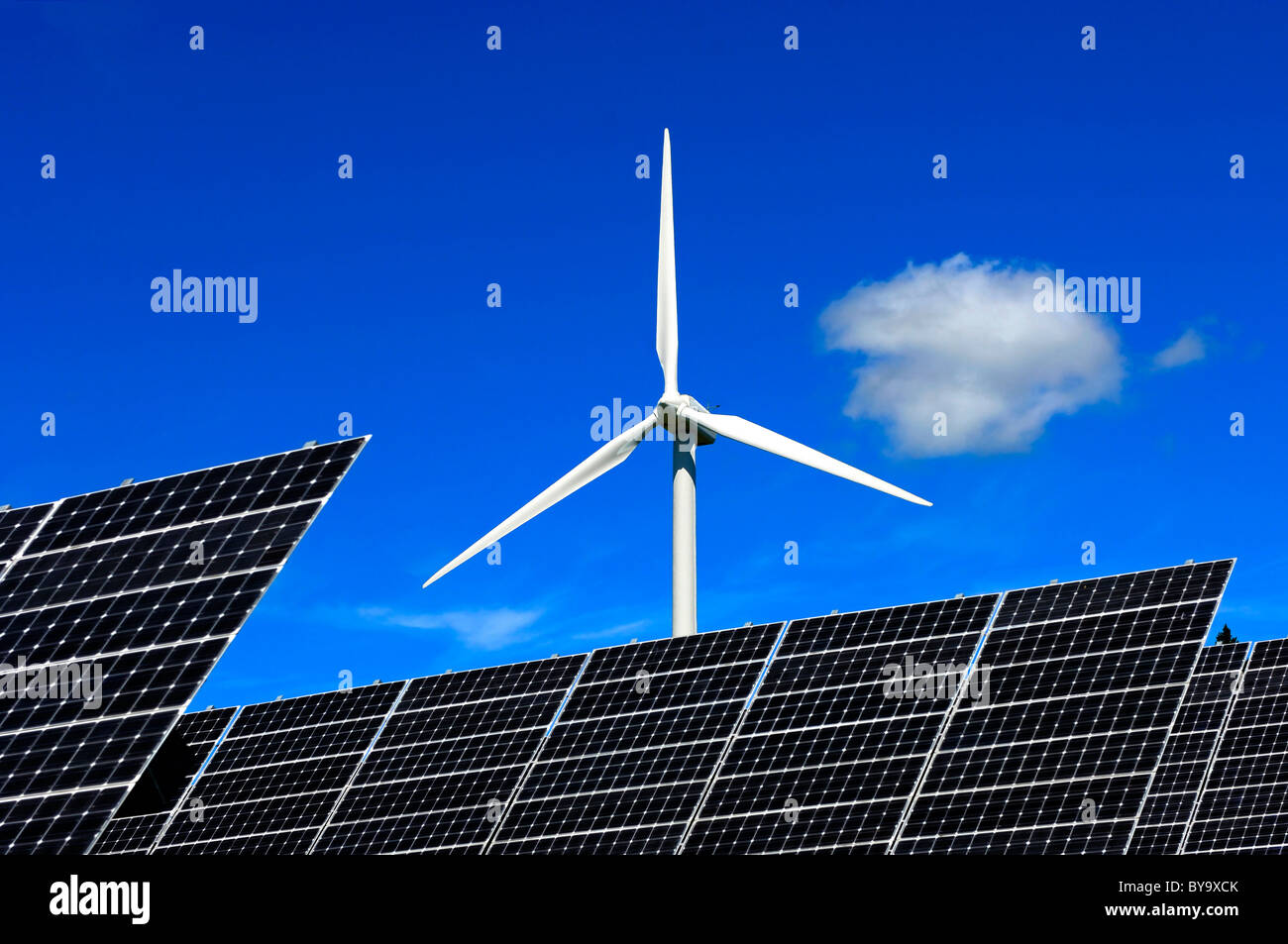 Solar panels of solar power farm in front of a wind turbine, Photovoltaics centre Mont Soleil, Switzerland Stock Photo