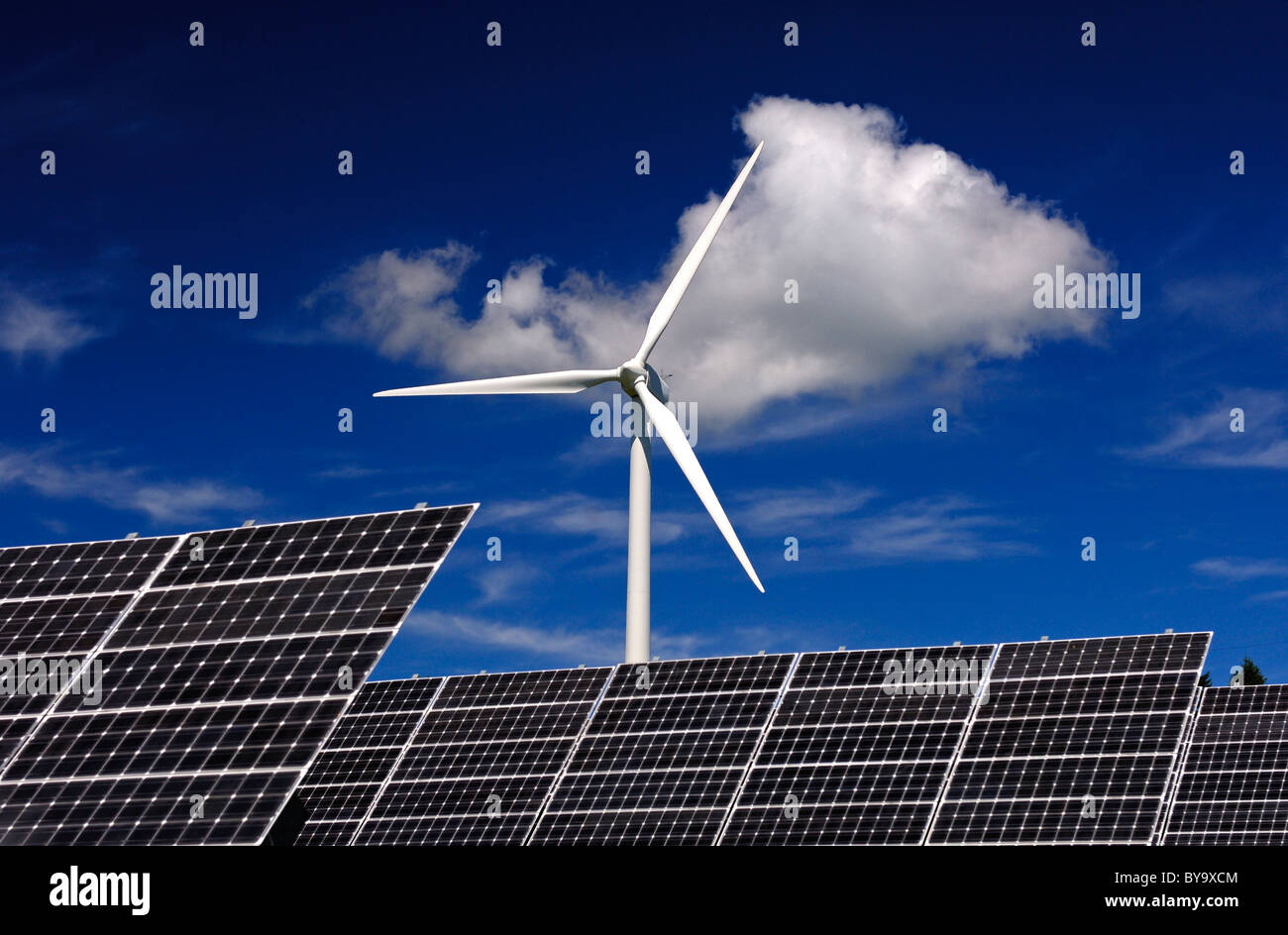 Solar panels of solar power farm in front of a wind turbine, Photovoltaics centre Mont Soleil, Switzerland Stock Photo