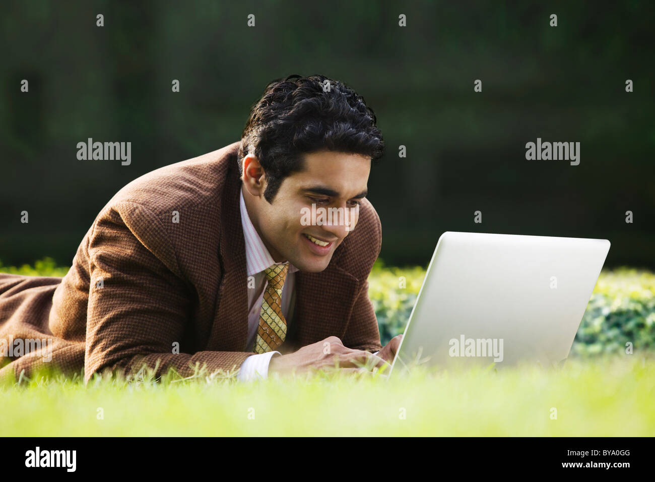 Businessman with a laptop in a park Stock Photo - Alamy